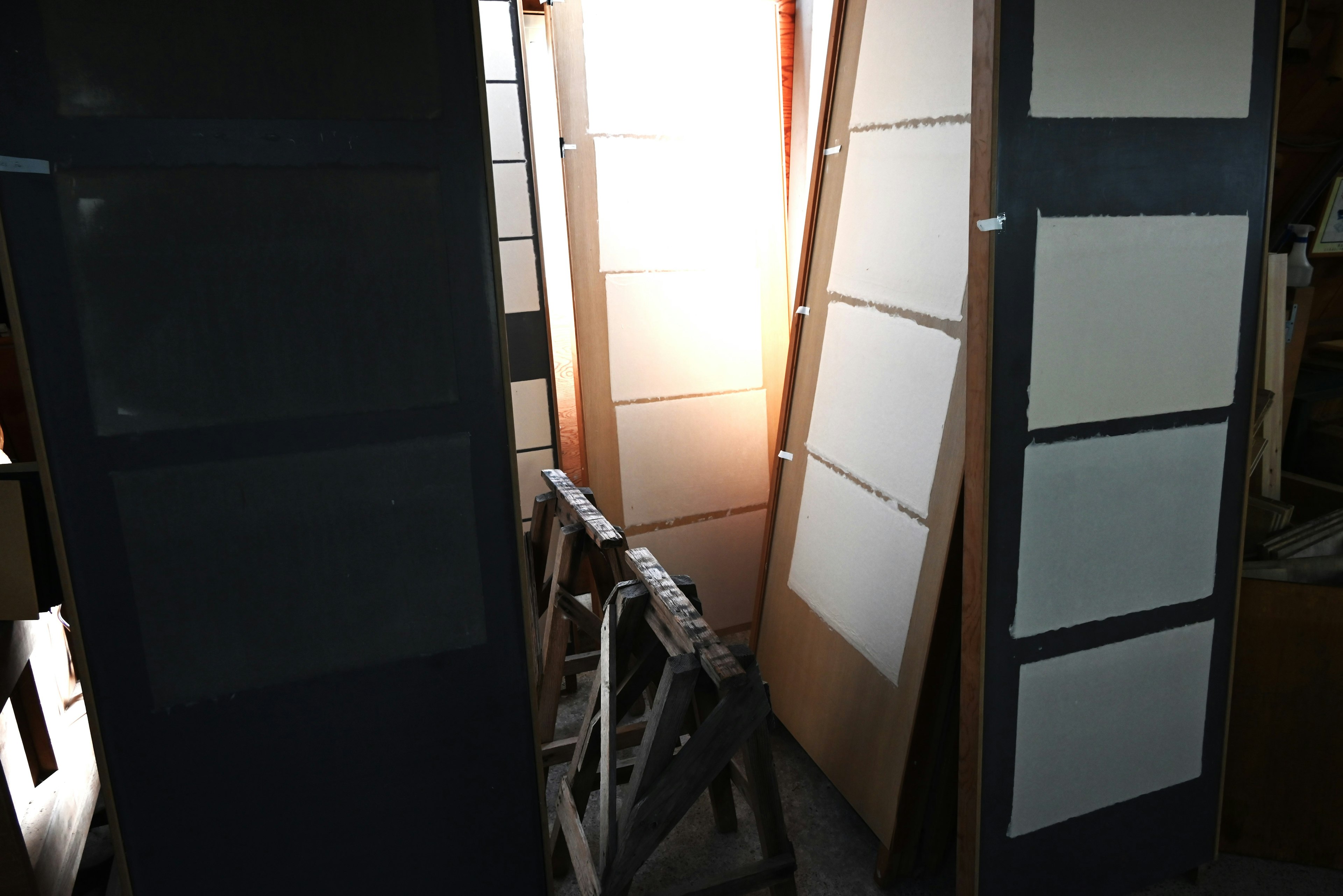 An interior workspace featuring white boards leaning against dark frames illuminated by bright light