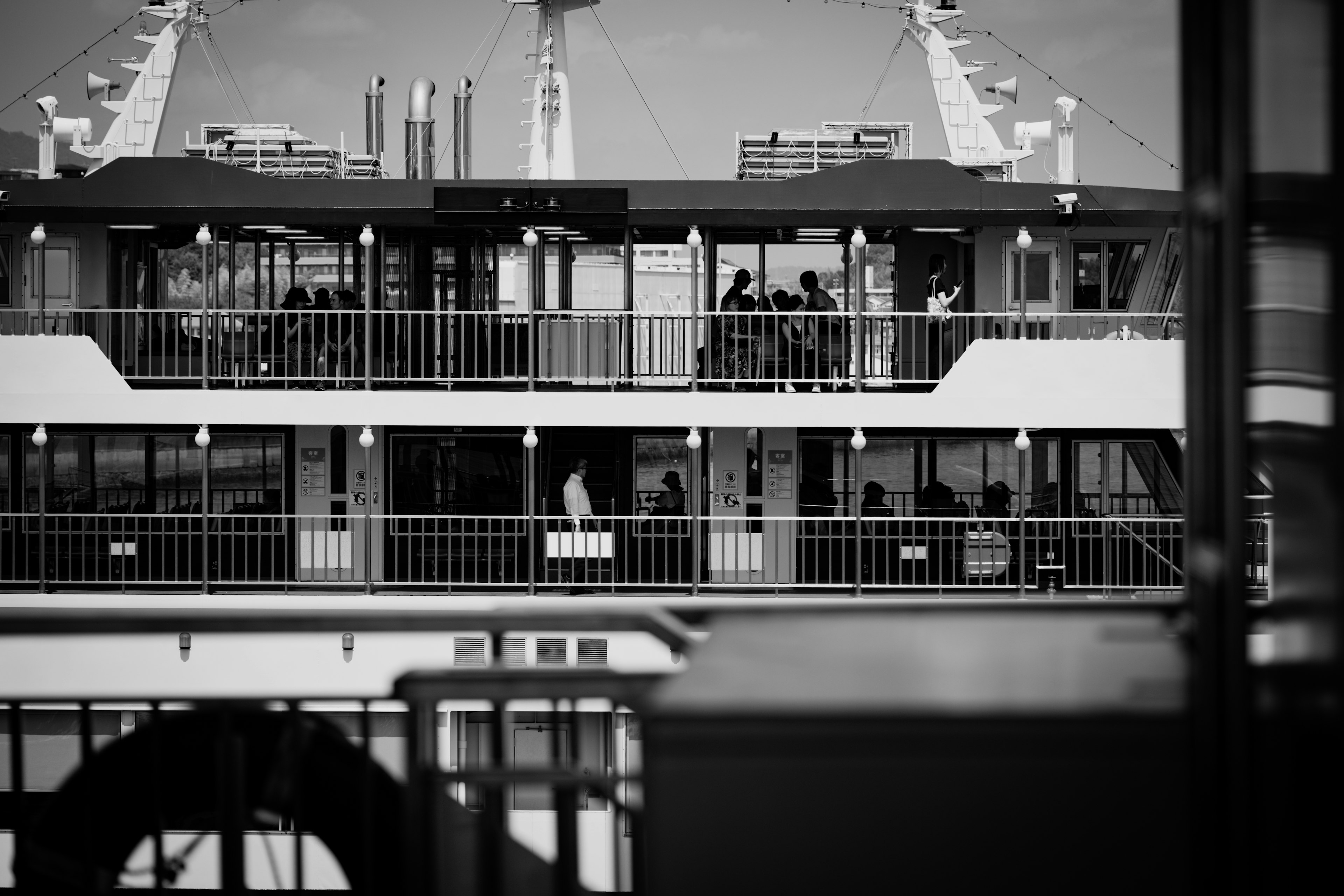 Black and white image of a ferry's interior structure with silhouettes of people