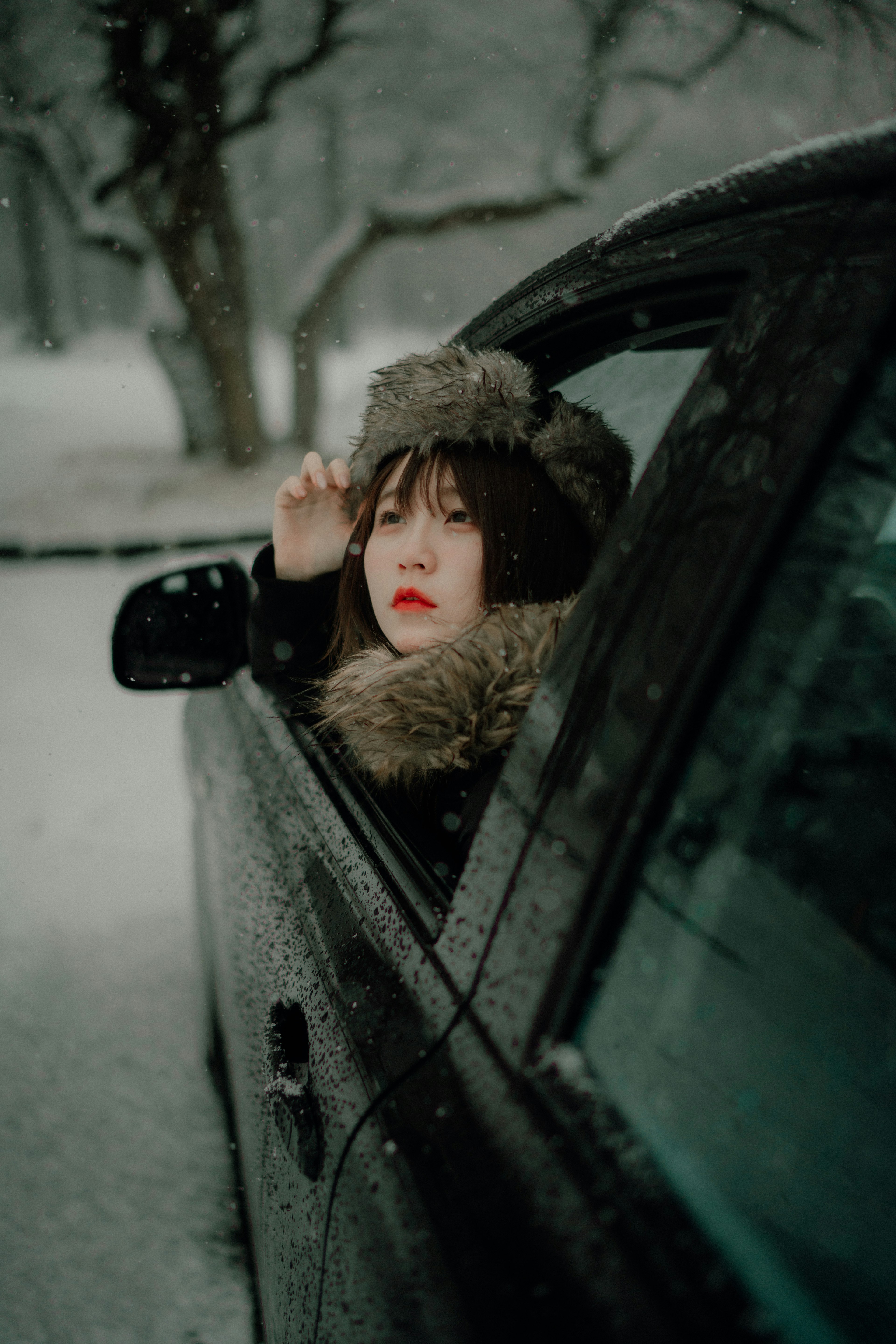 雪の中で車の窓から外を見ている女性の横顔