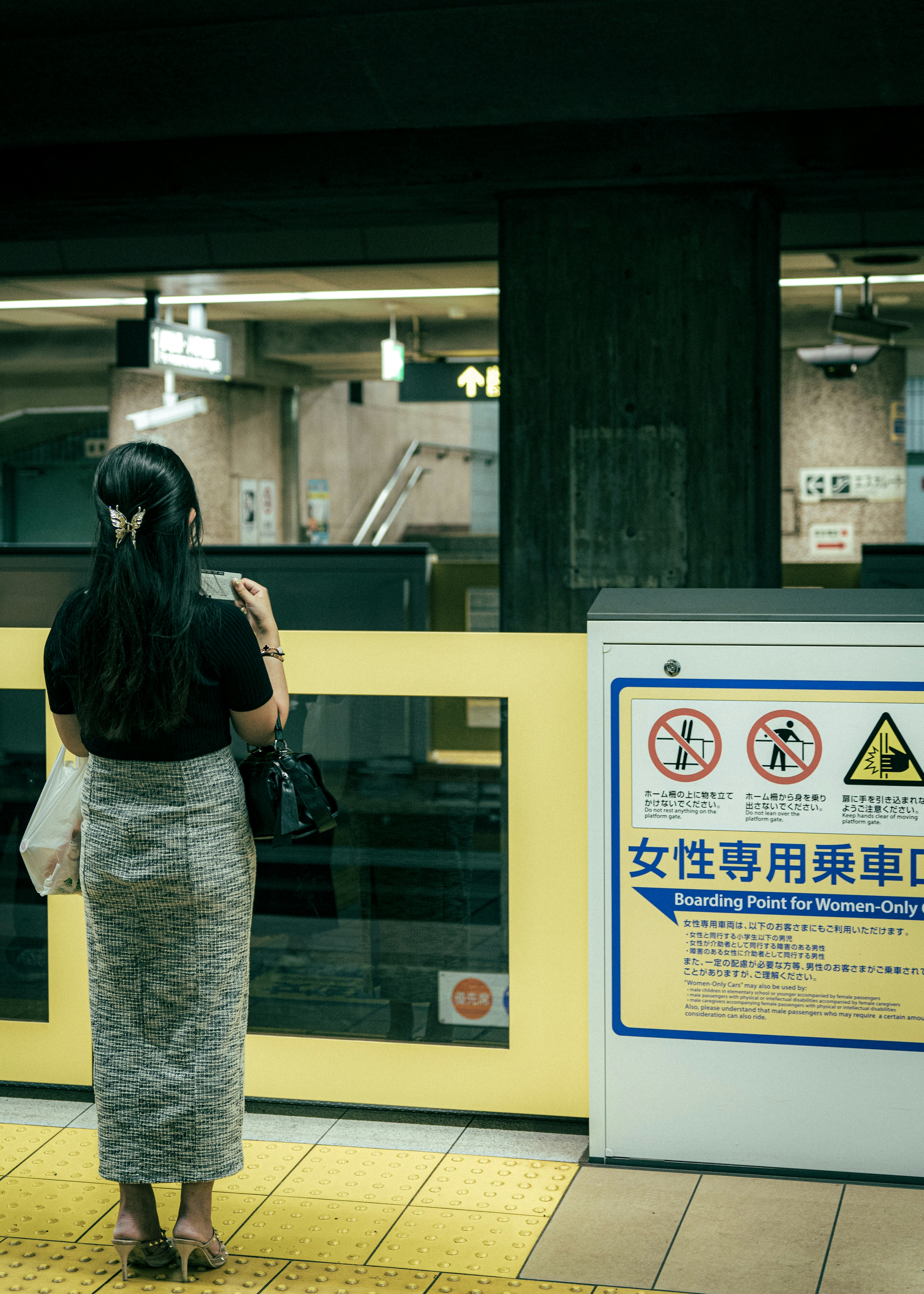 女性が地下鉄のホームで列車を待っている