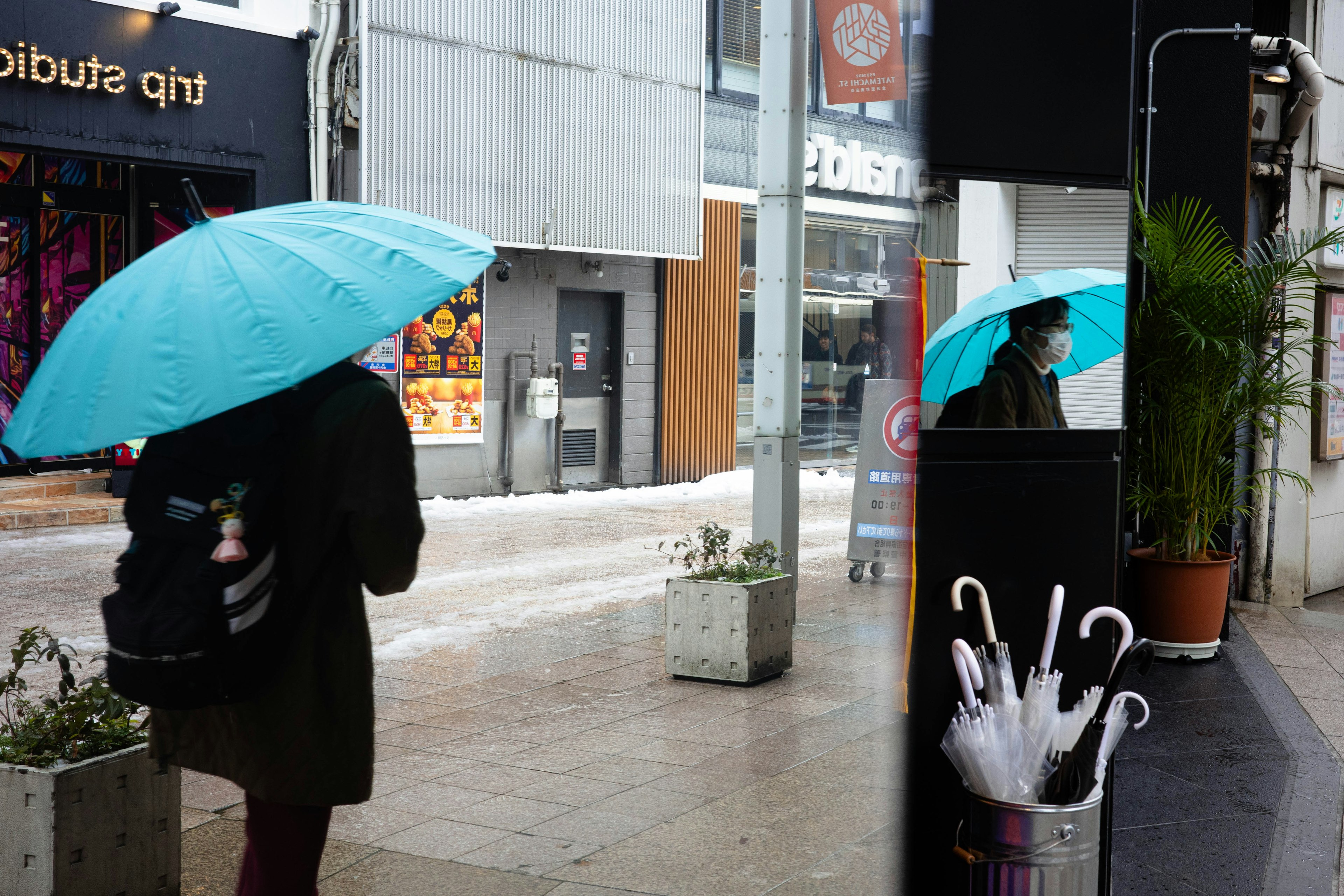 一个人手持蓝色雨伞在街上行走