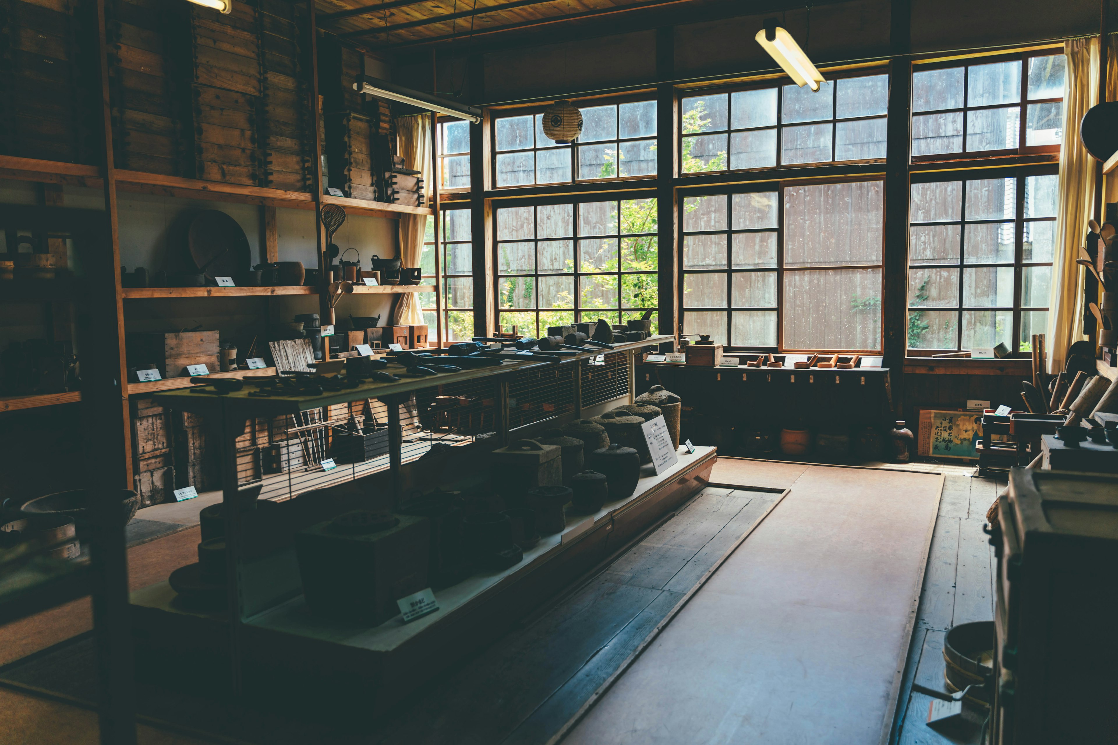 Bright interior of a workshop with large windows wooden shelves filled with tools and a workbench in the center