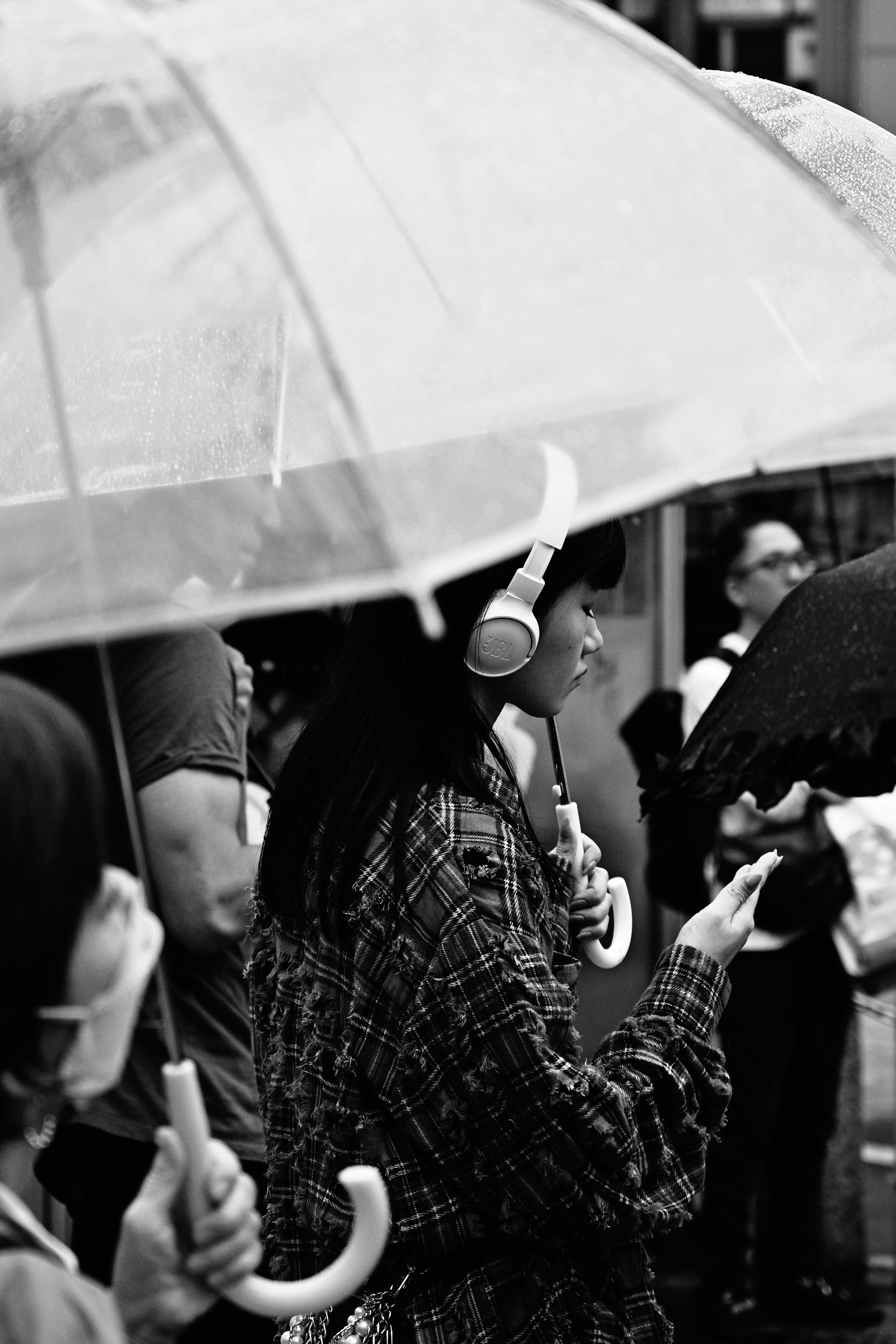 Femme écoutant de la musique sous un parapluie avec des gens autour