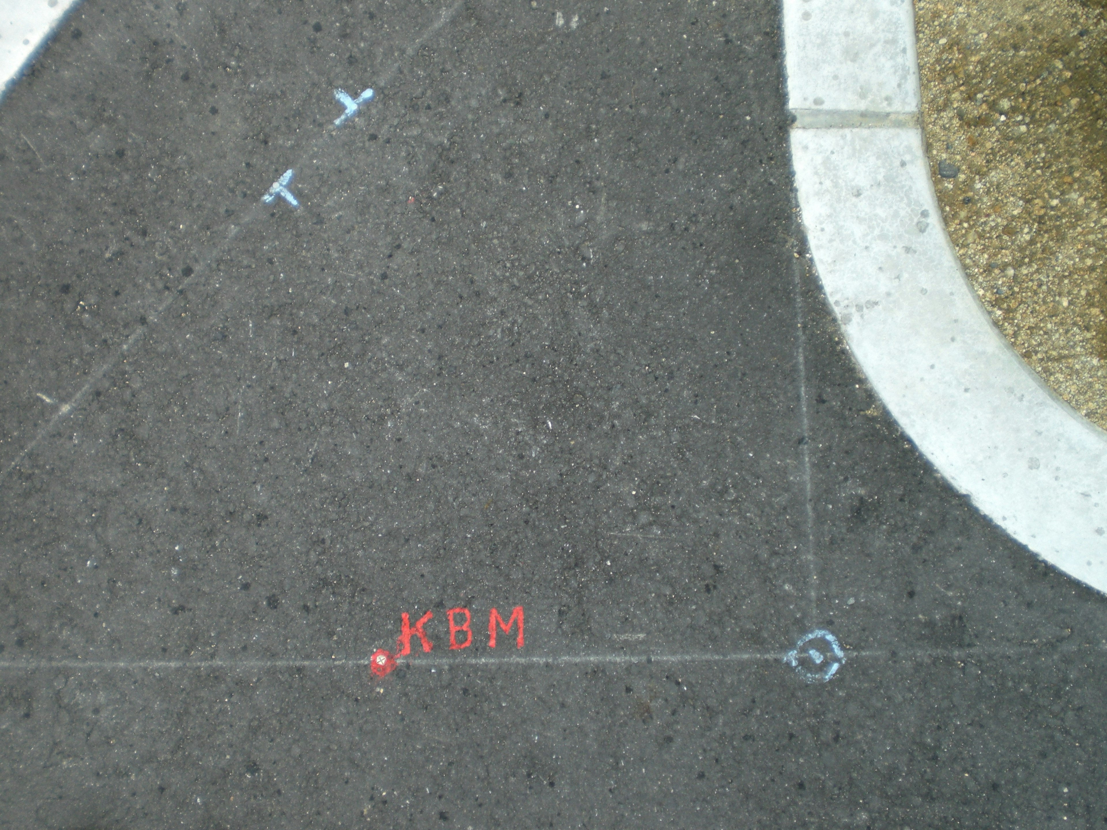 Surveying marks and blue arrows on asphalt surface