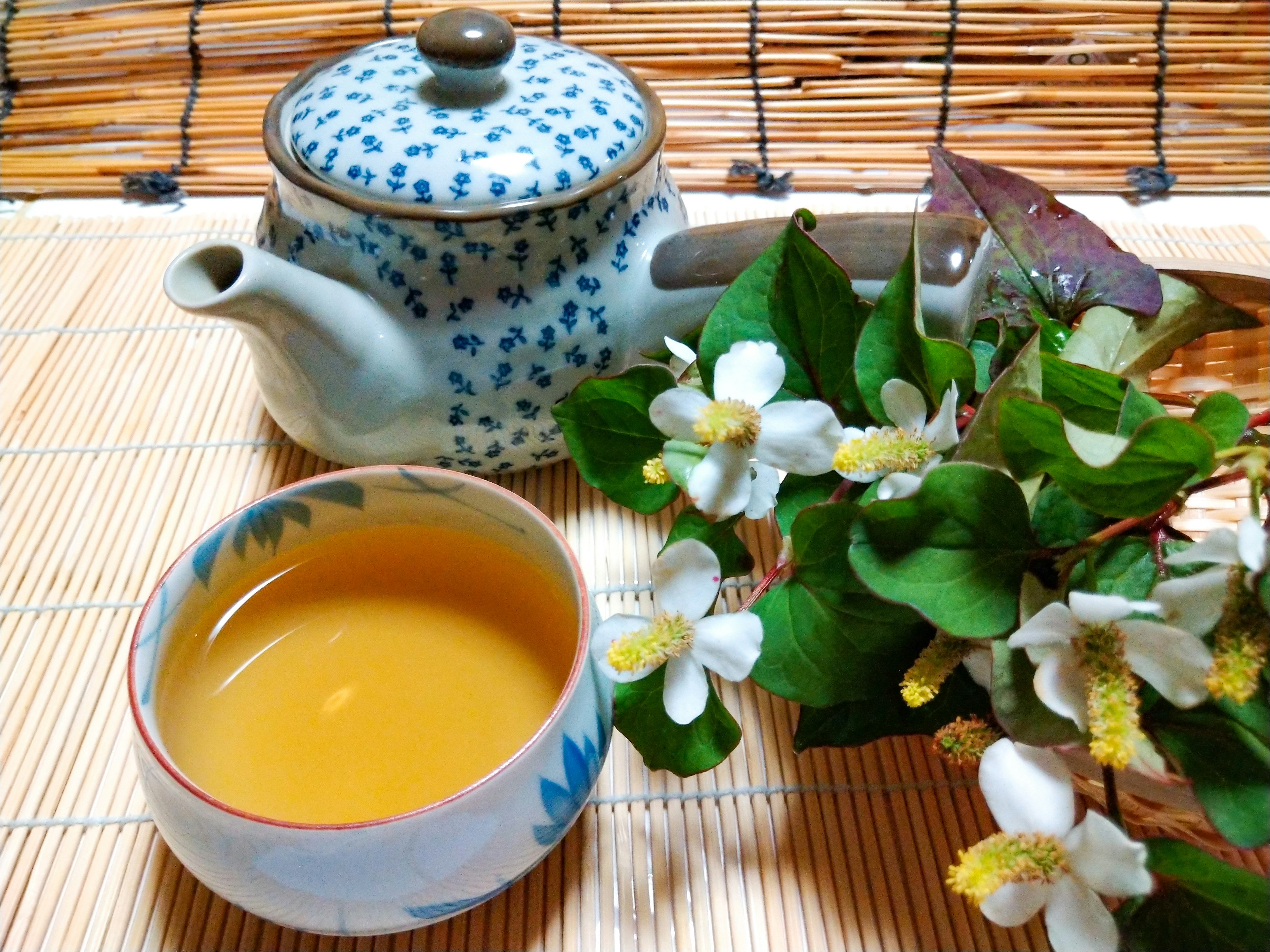 青い模様の急須とお茶碗に入ったお茶と花のある美しいテーブルセッティング