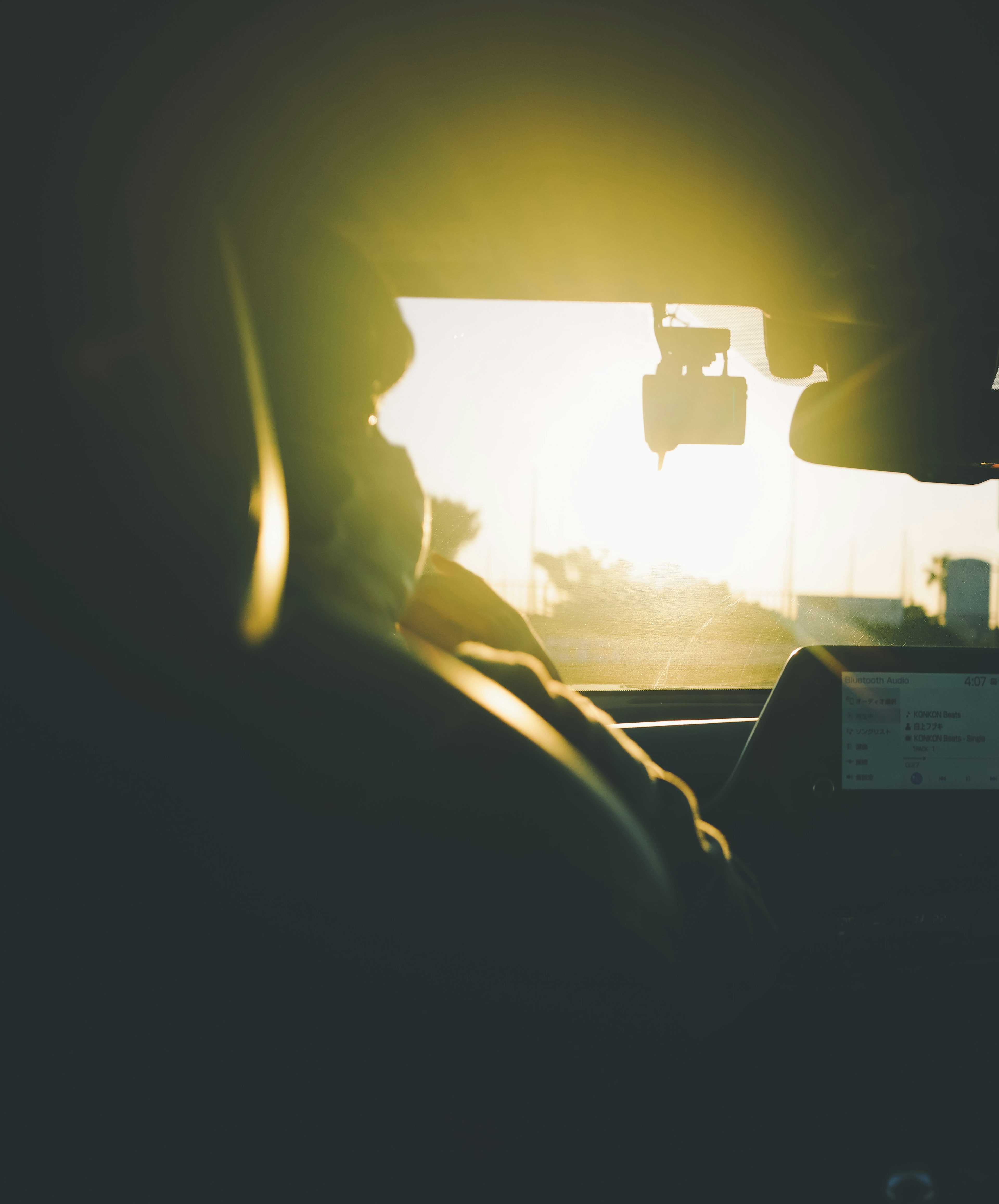 Silhouette d'un conducteur avec vue sur le coucher de soleil depuis l'intérieur d'une voiture