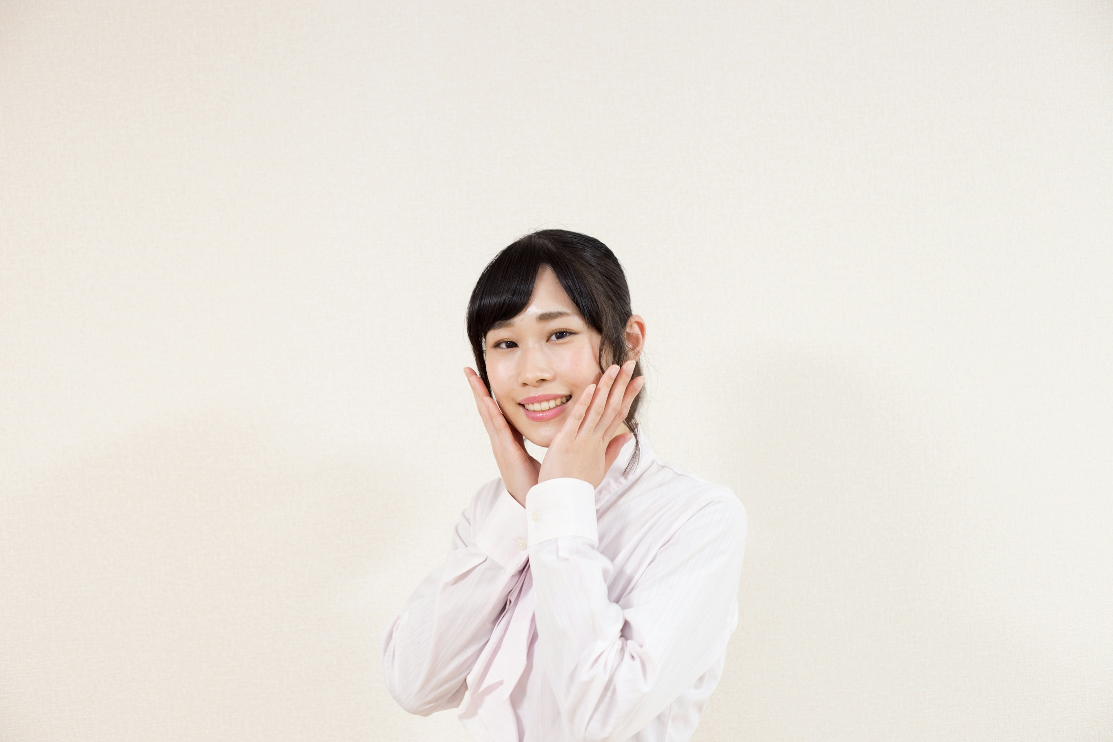 Smiling woman with hands on her face in front of a white background