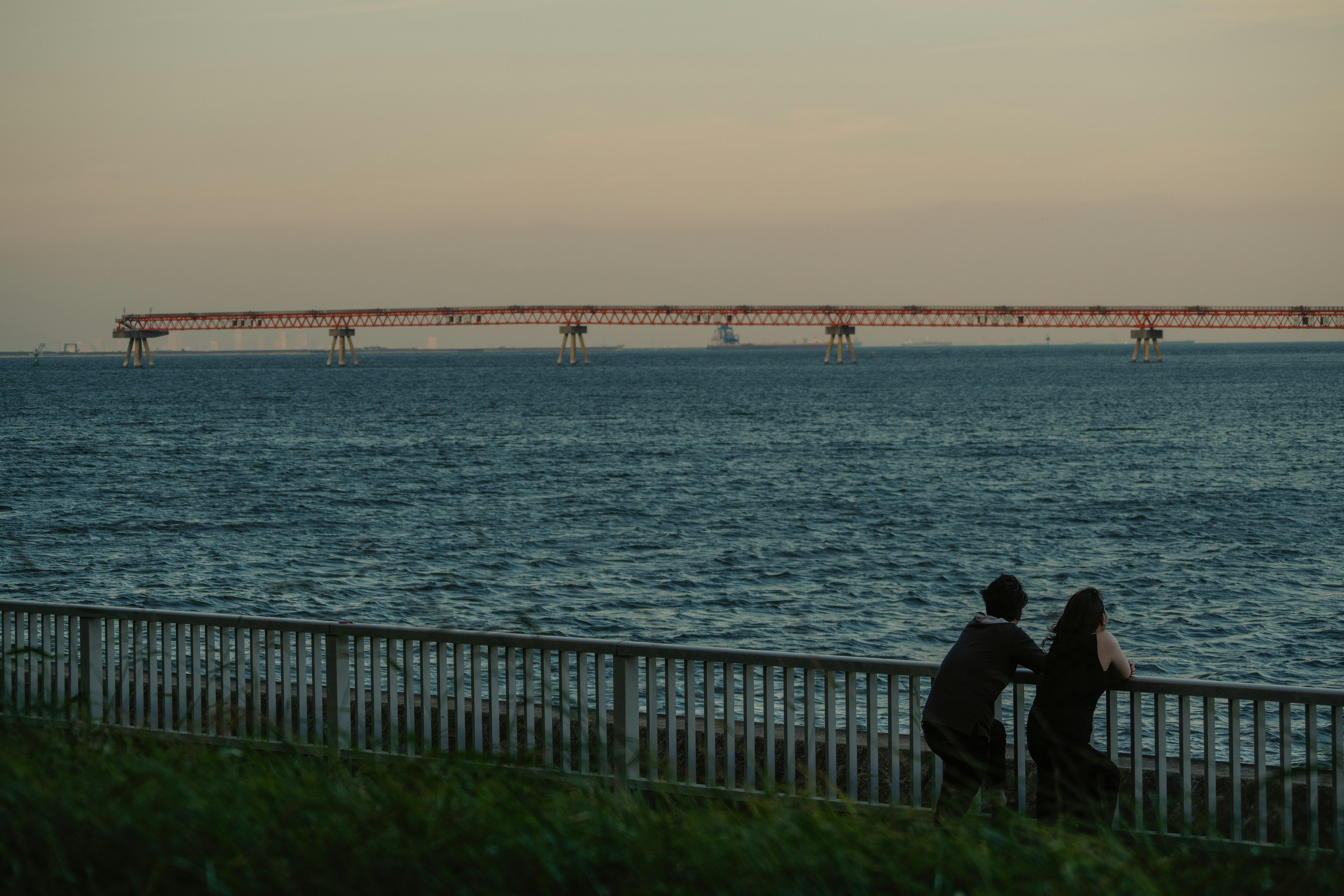 Couple embracing by the seaside with a distant bridge