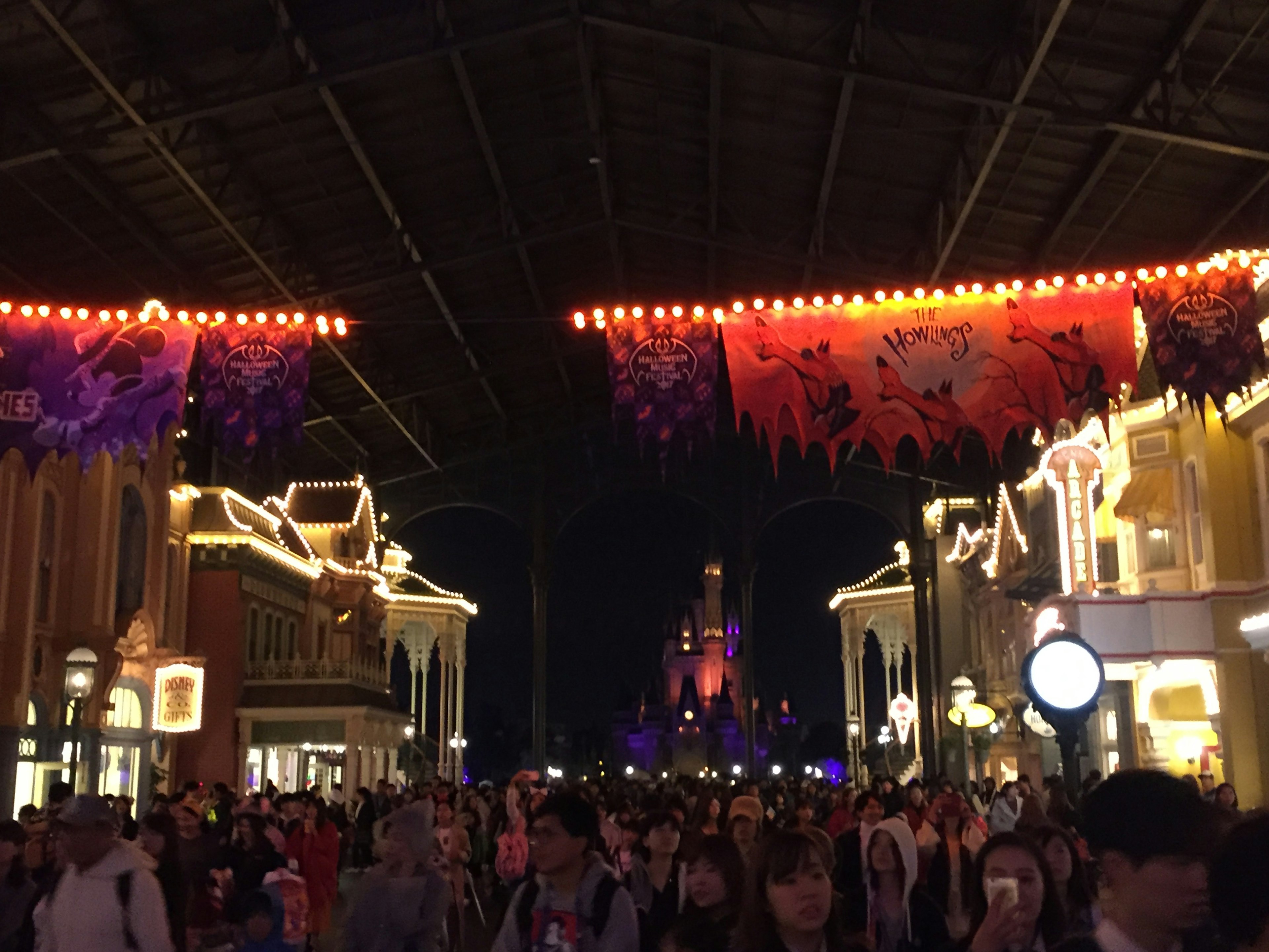 Foule dans une rue de parc à thème la nuit avec des lanternes décorées