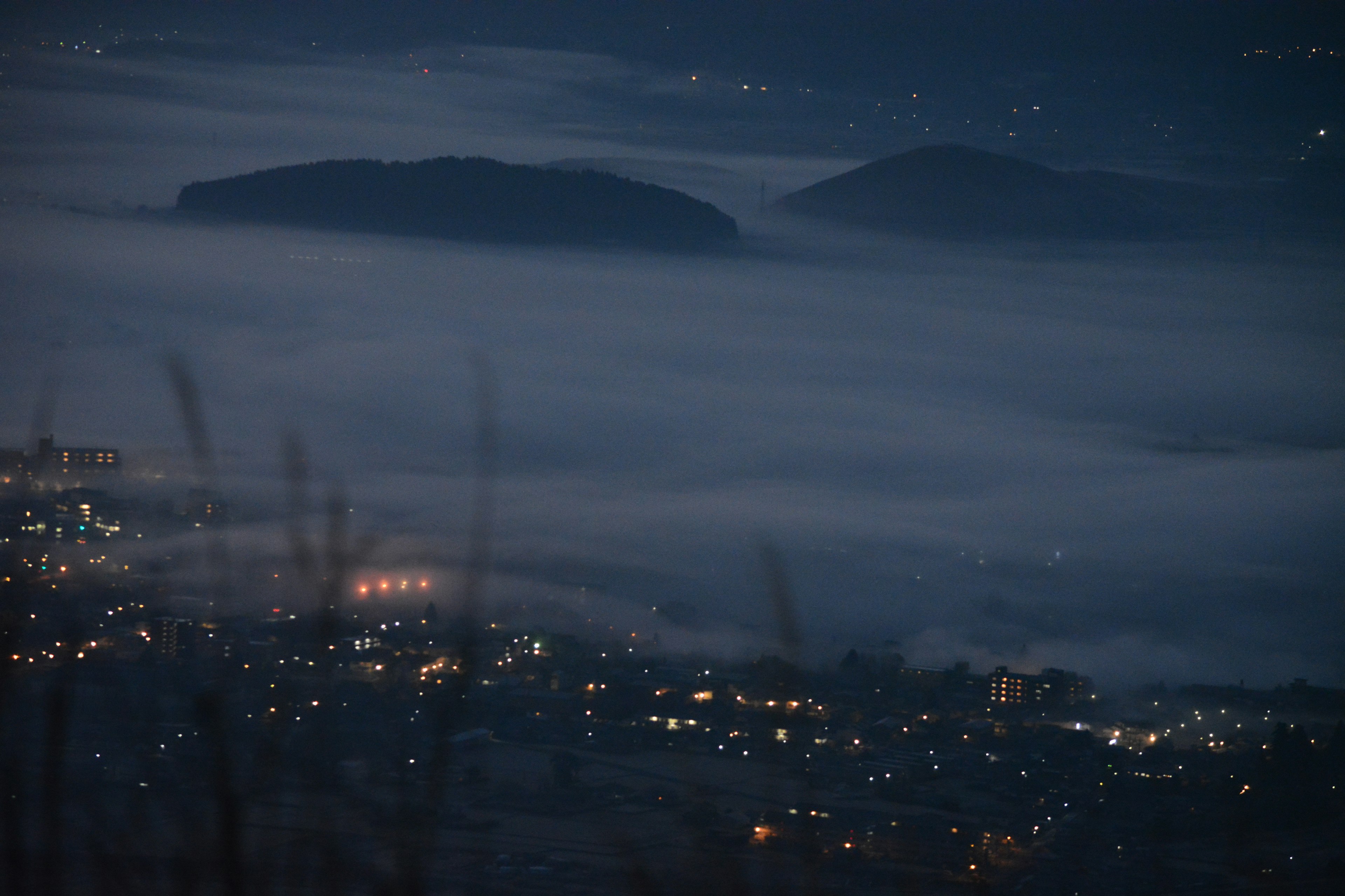 Paisaje nocturno con islas cubiertas de niebla y luces de la ciudad