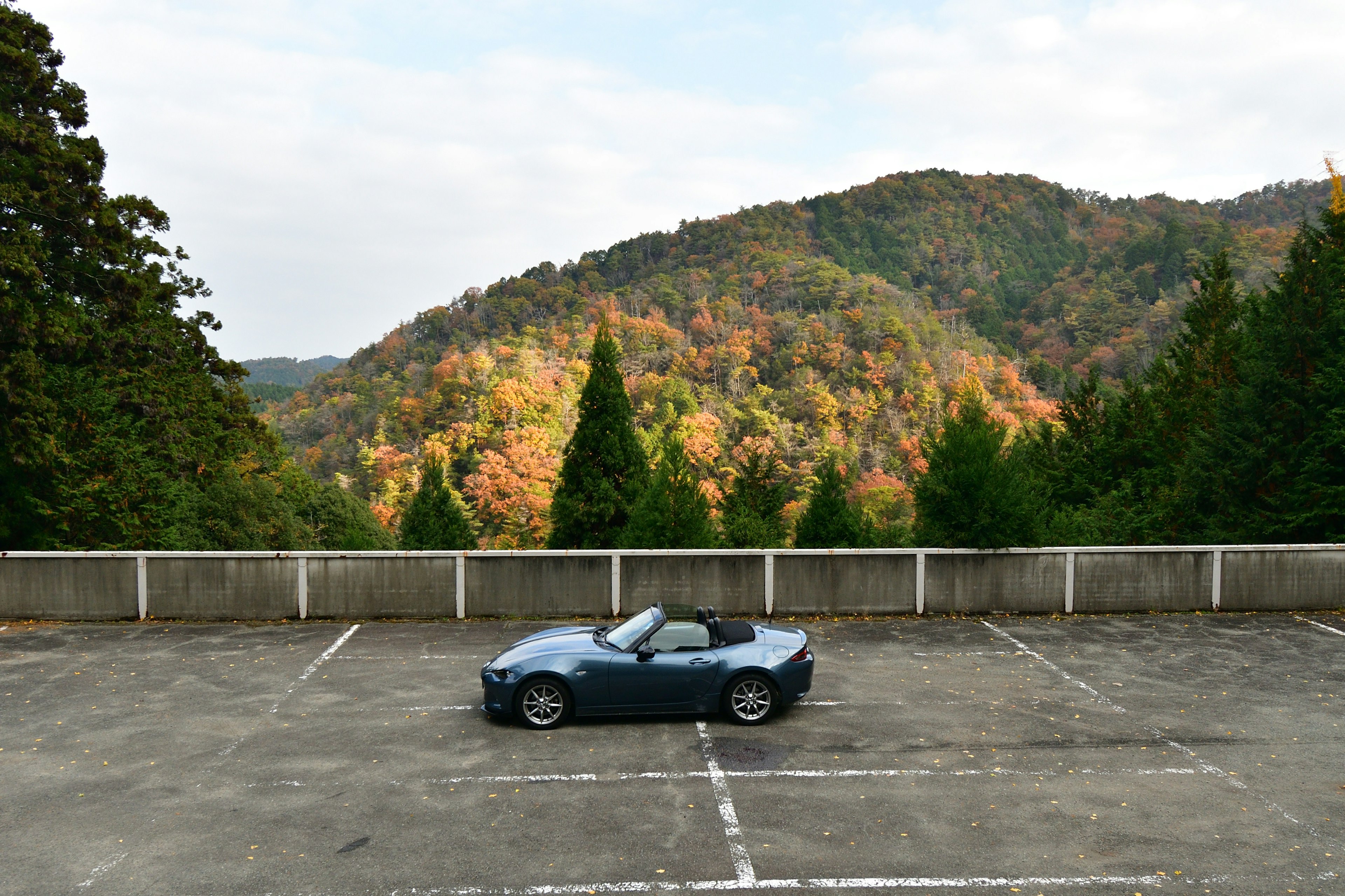 Image of a blue convertible car with a mountainous landscape in the background