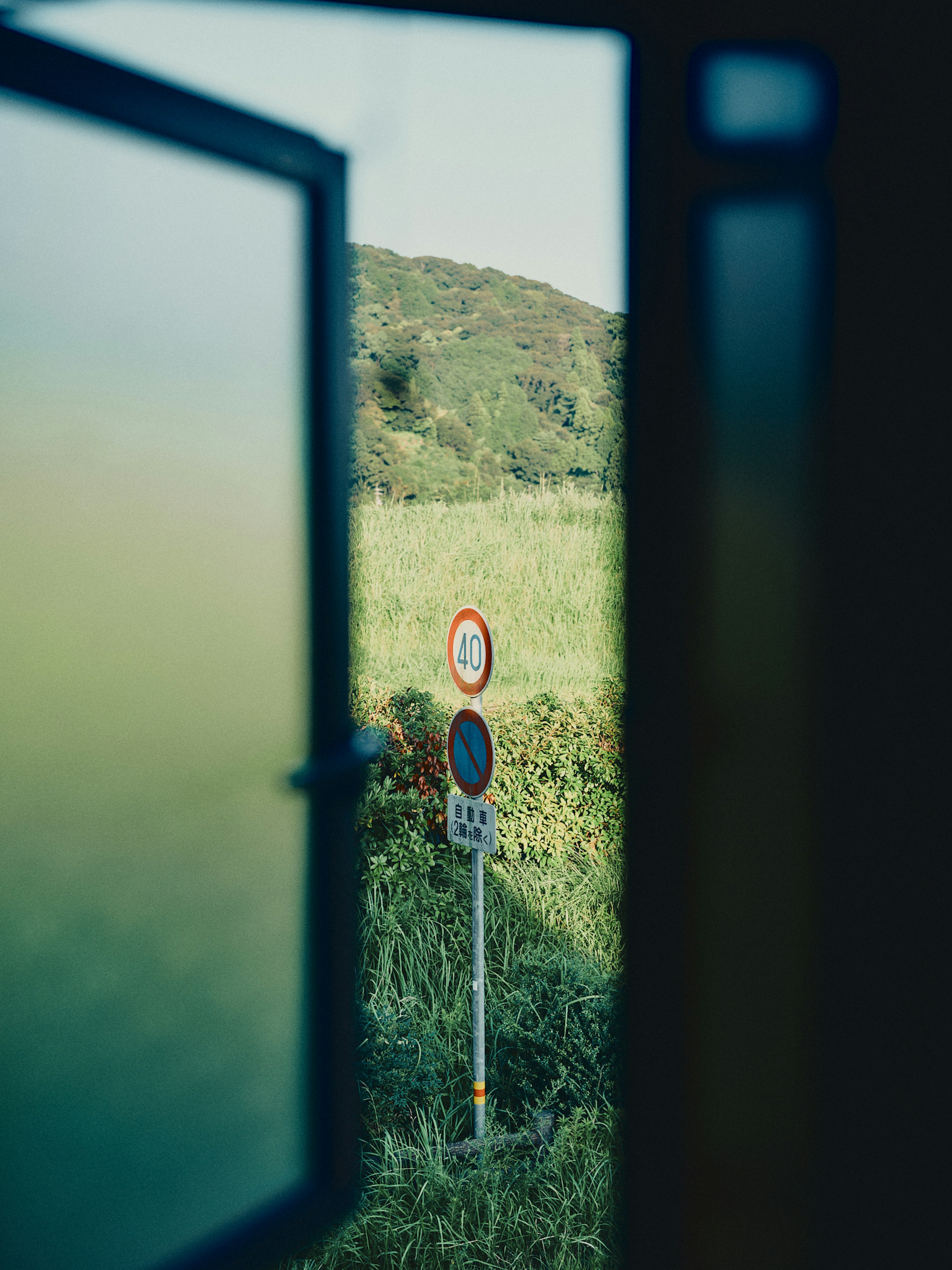 Vista a través de una ventana que muestra un campo de hierba y señales de tráfico