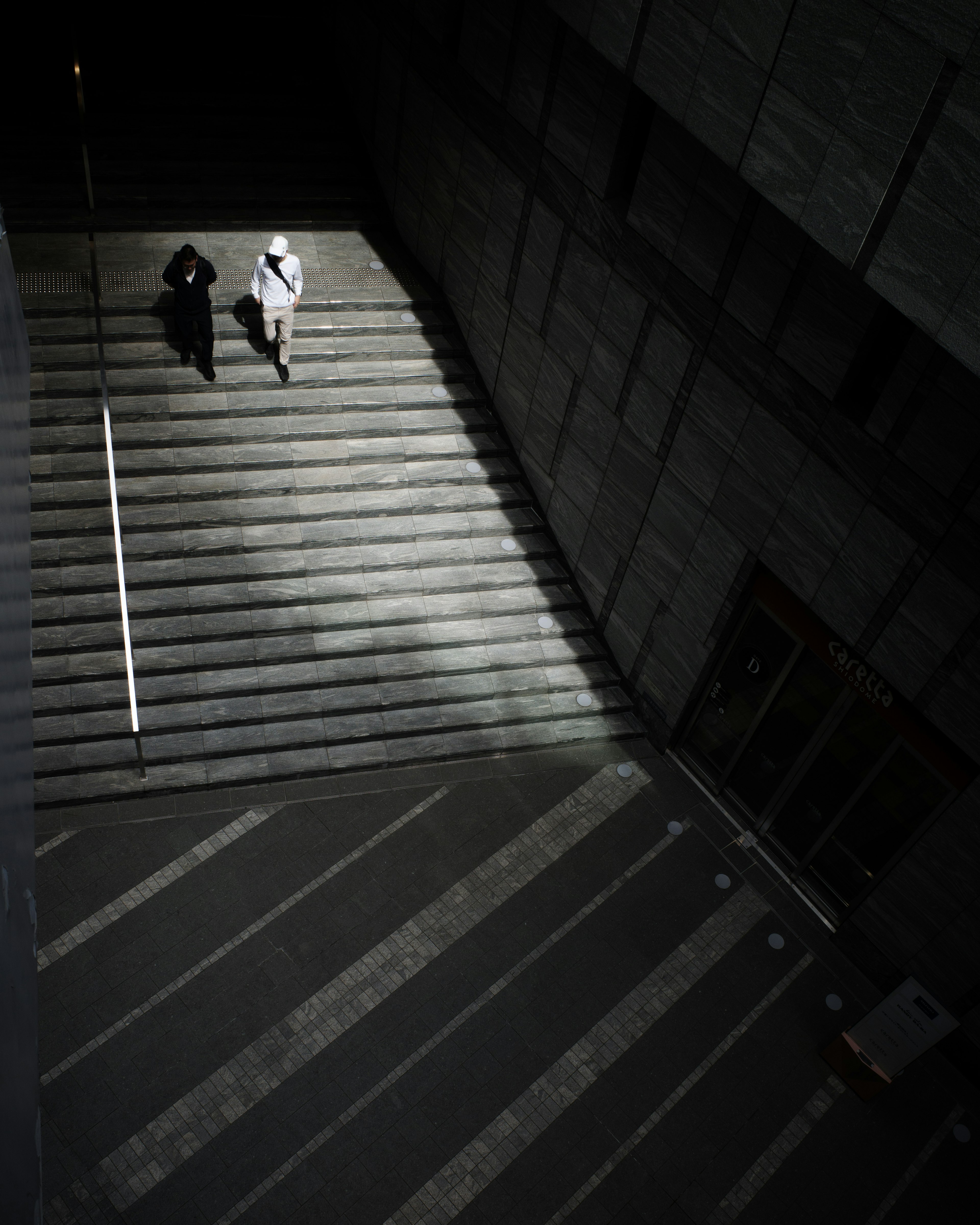 Due figure che camminano giù per le scale con luce e ombra contrastanti