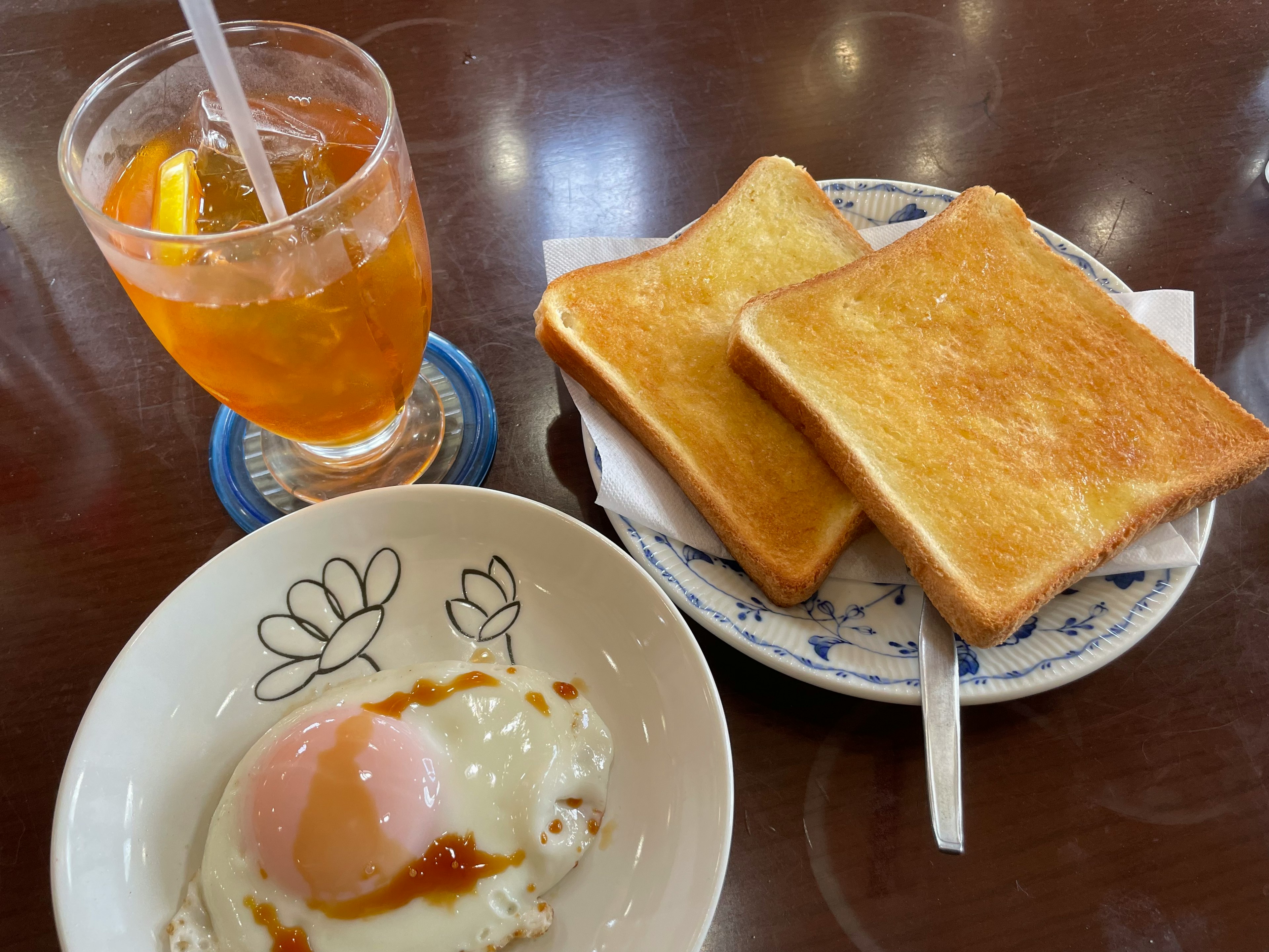 トーストと温泉卵の朝食セットにオレンジスライス入りのアイスティー