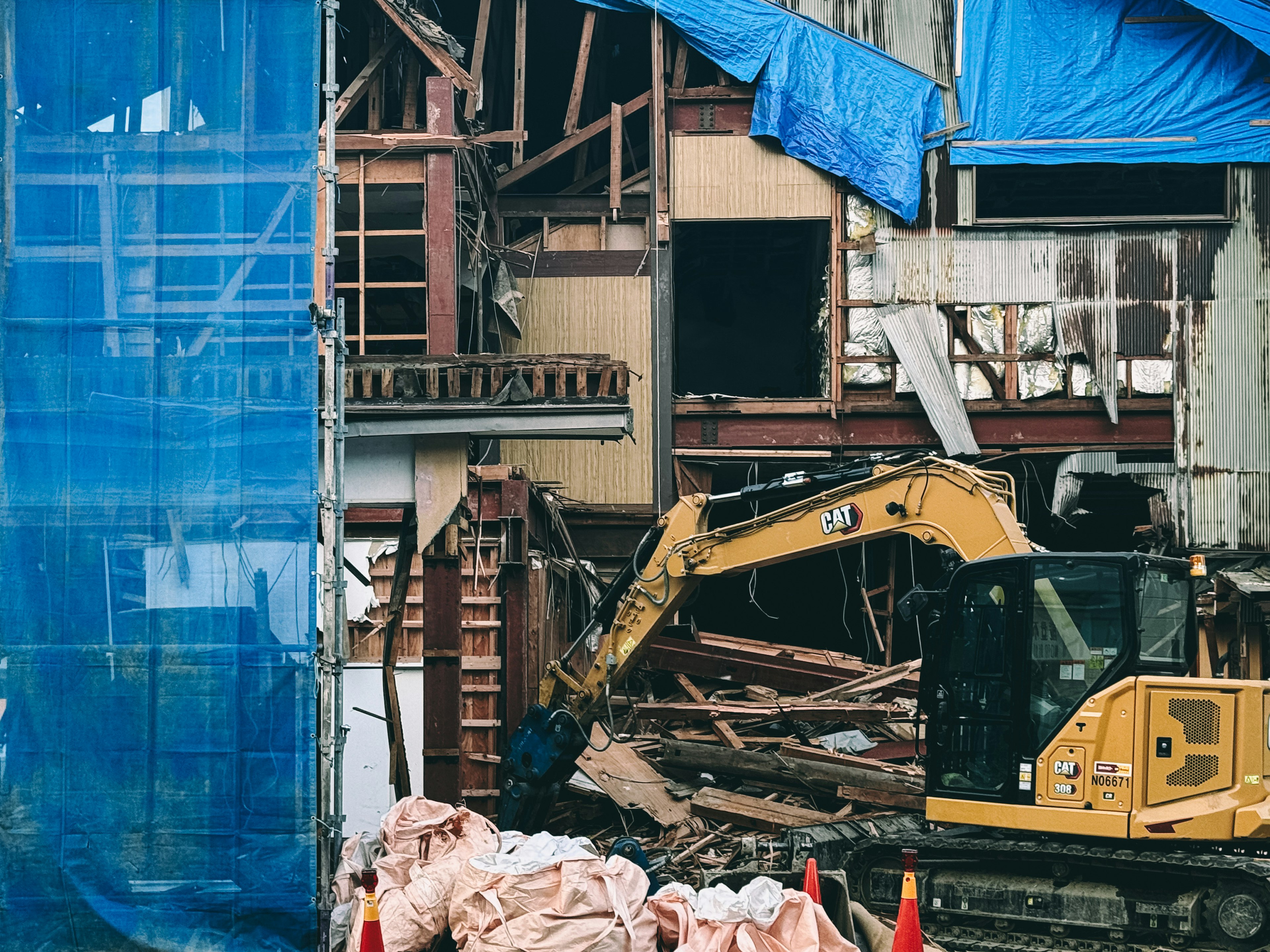 Demolition site with blue tarps and heavy machinery visible