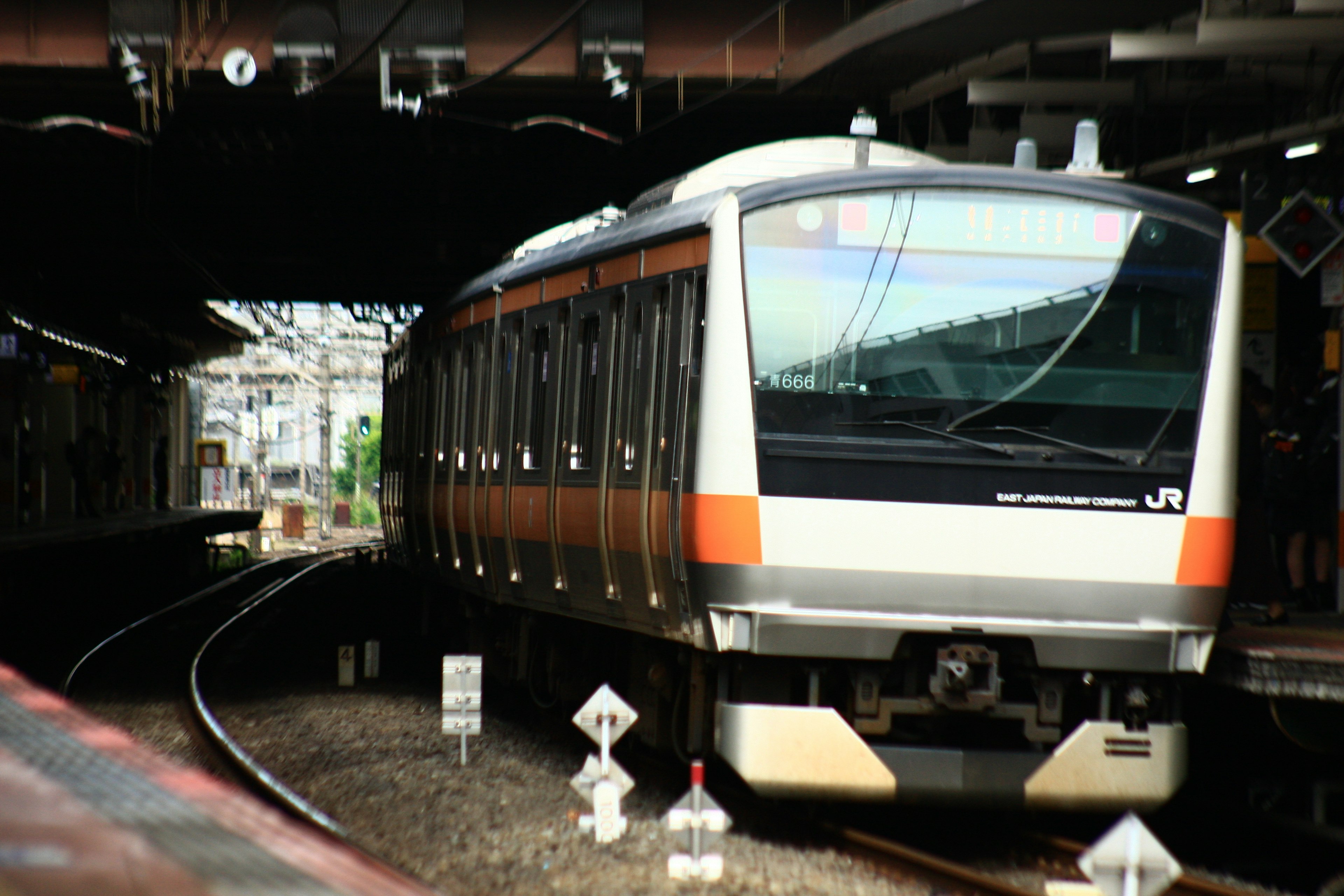 オレンジと白の電車がカーブを曲がりながらトンネルに入る風景