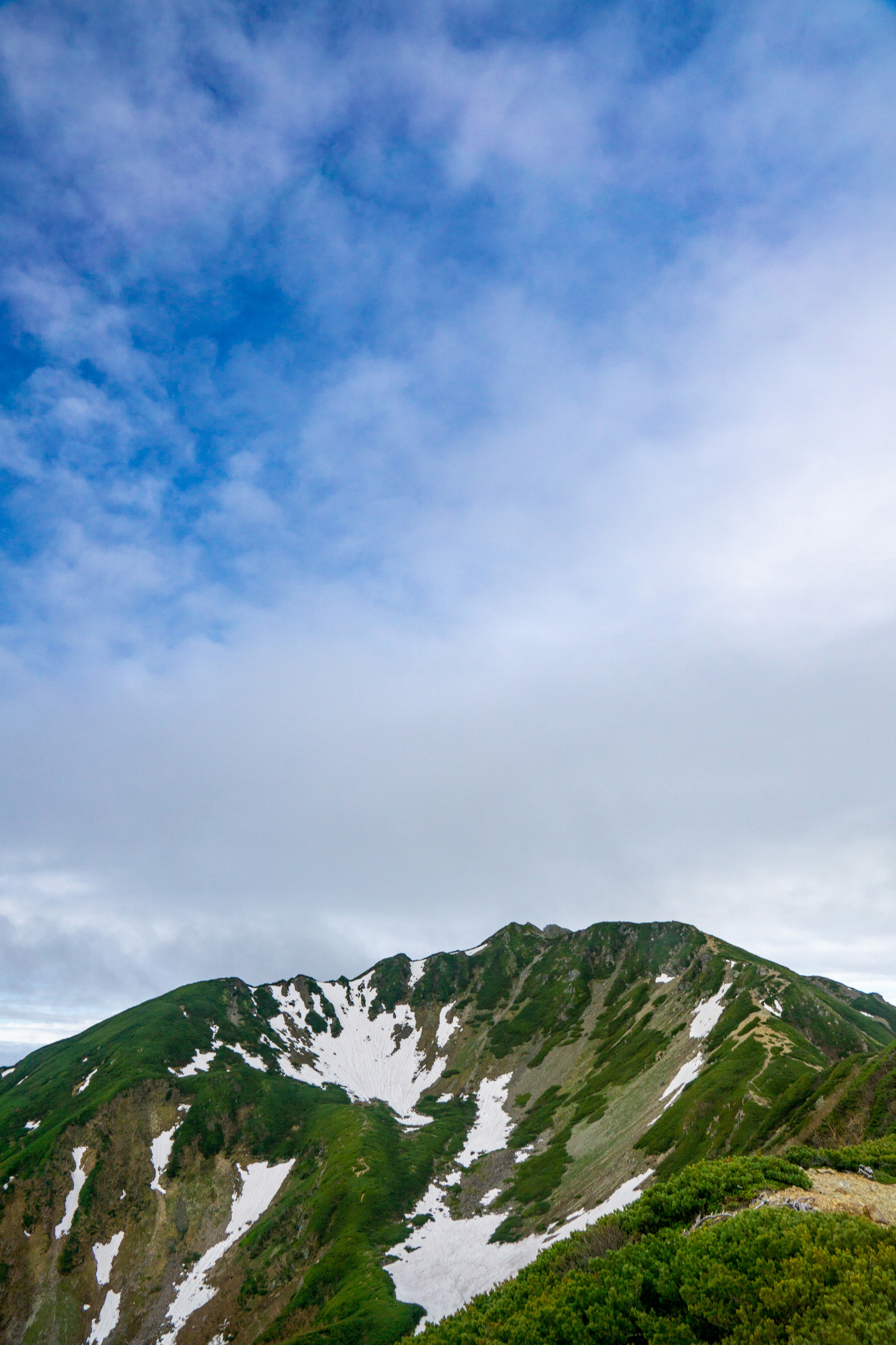 Berglandschaft mit grünem und weißem Schnee unter blauem Himmel