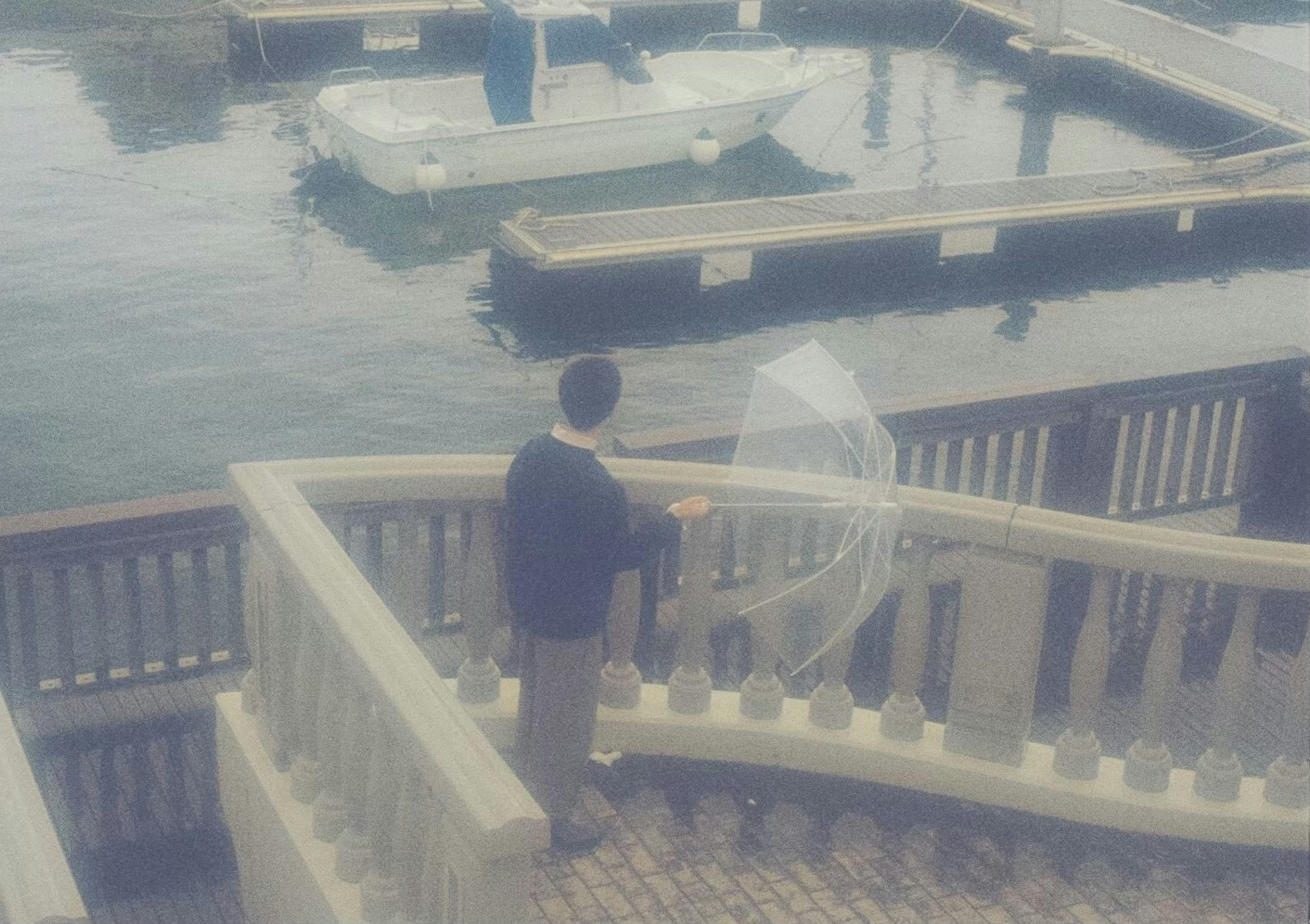 Person standing by the railing at a harbor with calm water