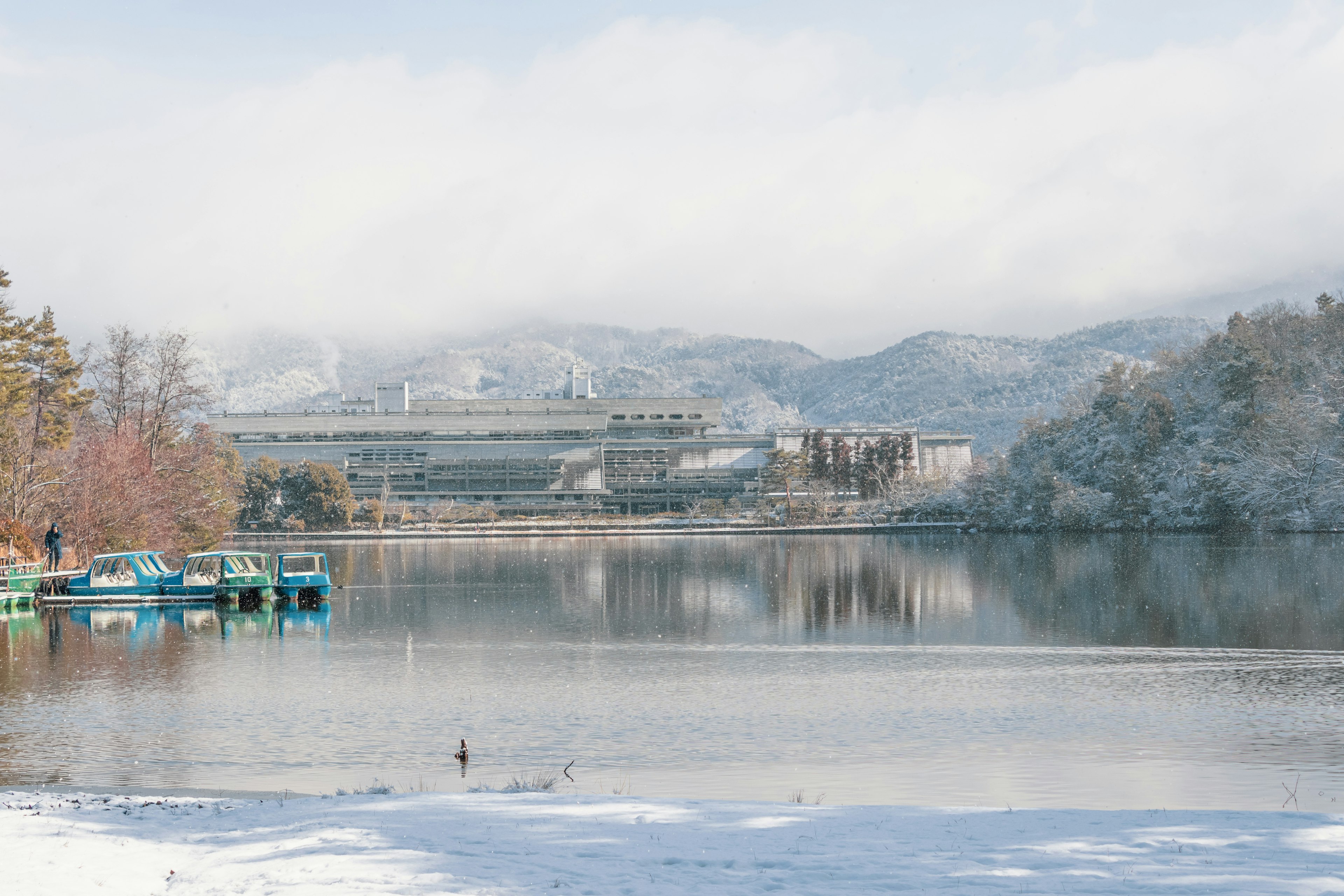 被雪覆盖的湖泊背景中的山脉停靠的船只