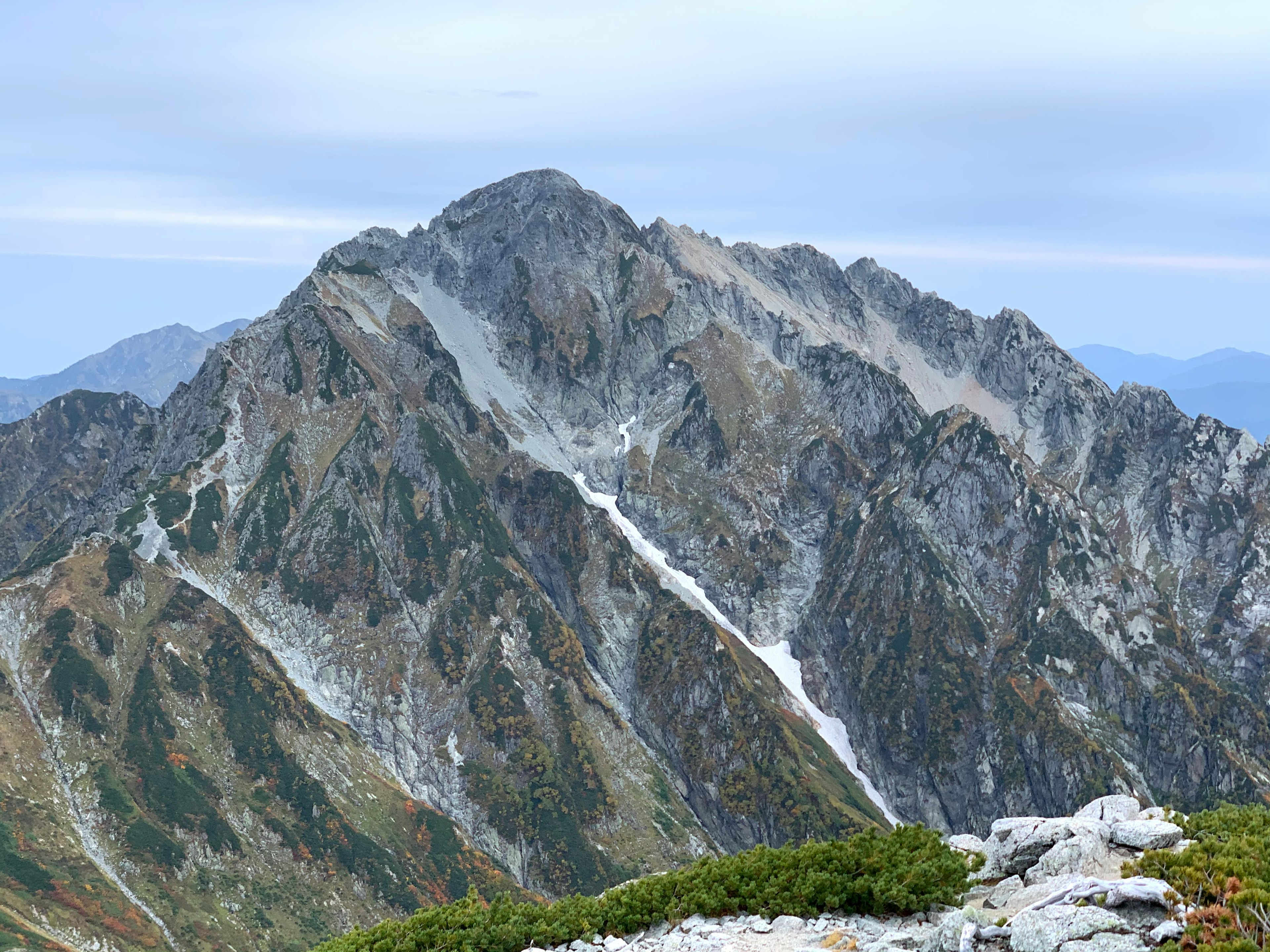 高い山の風景、岩の多い斜面、緑の低木が見える