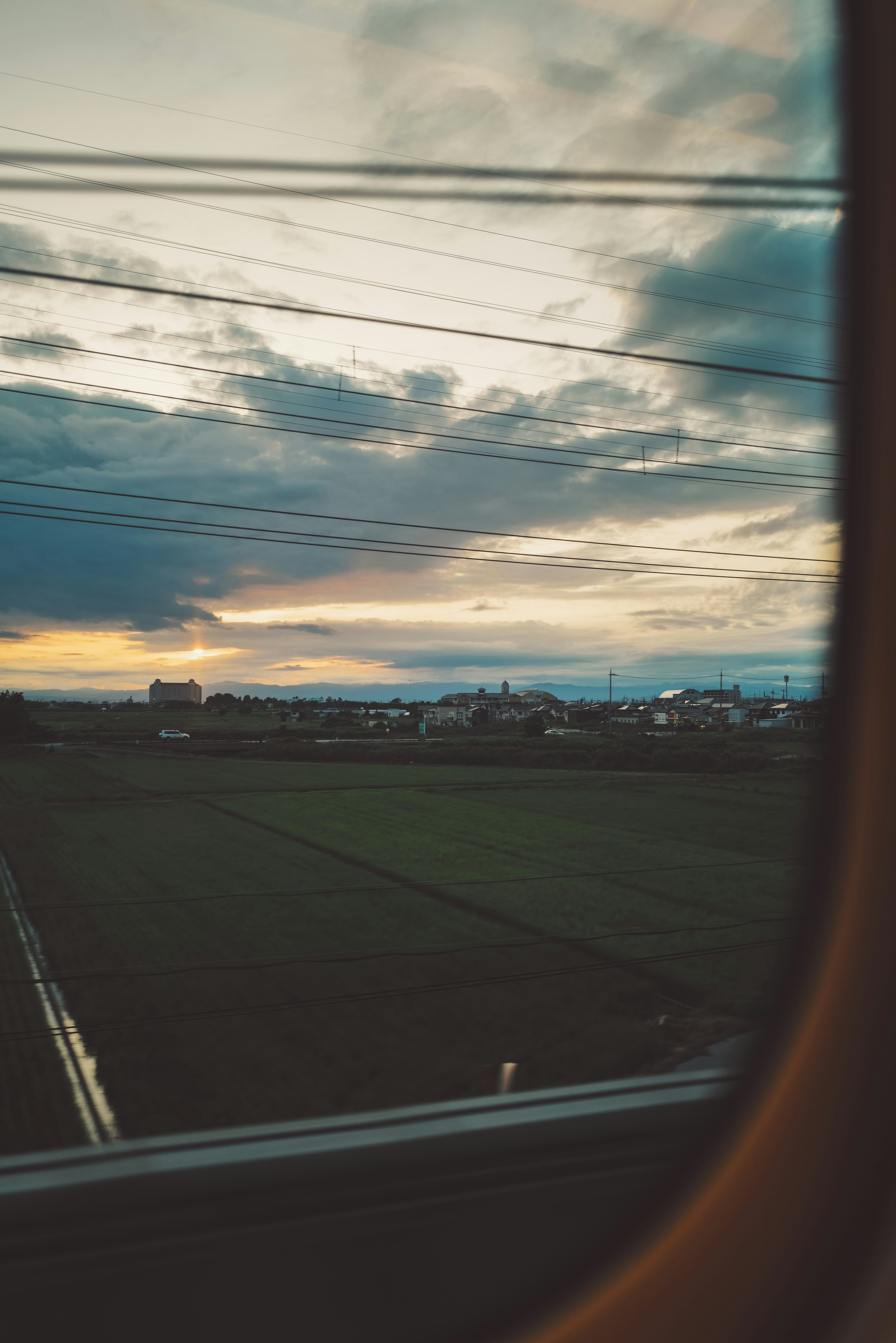 窓越しに見える田園風景と夕焼け空