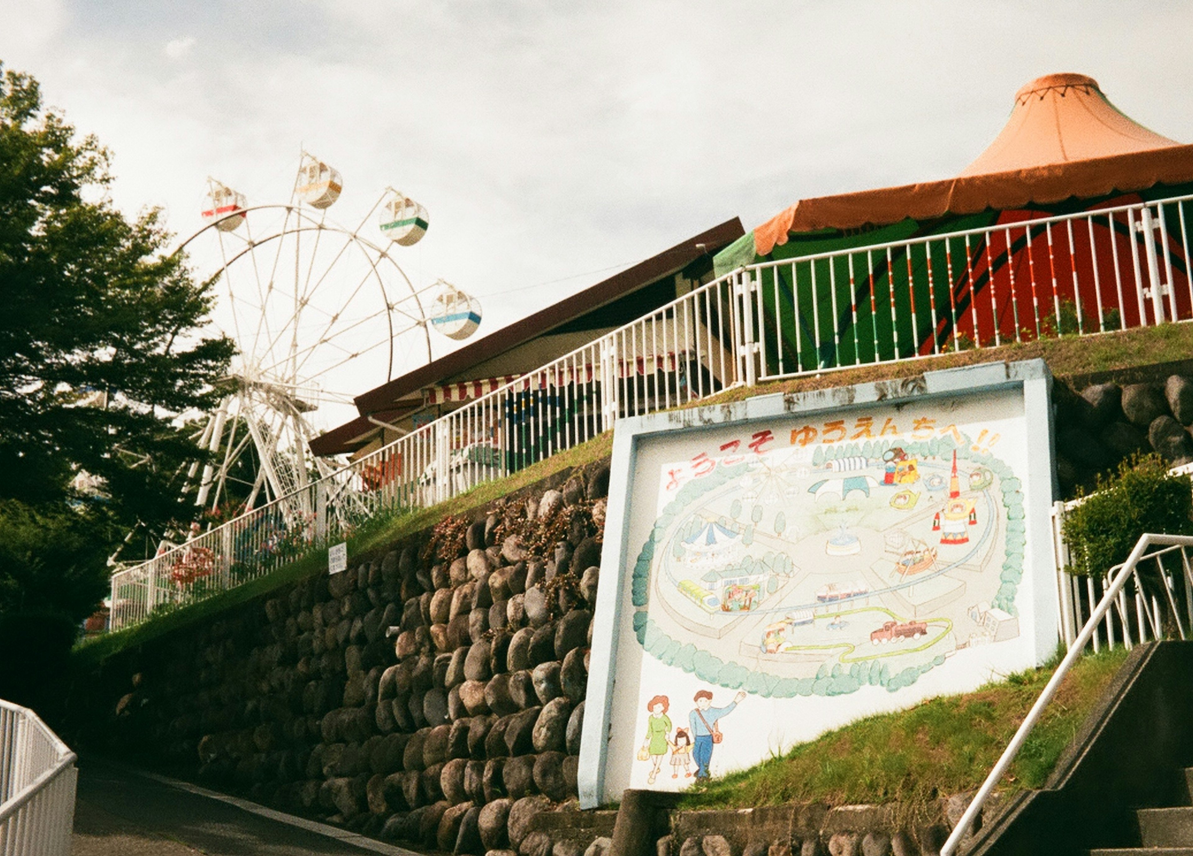 Vista di una ruota panoramica e di un muro con una mappa del parco