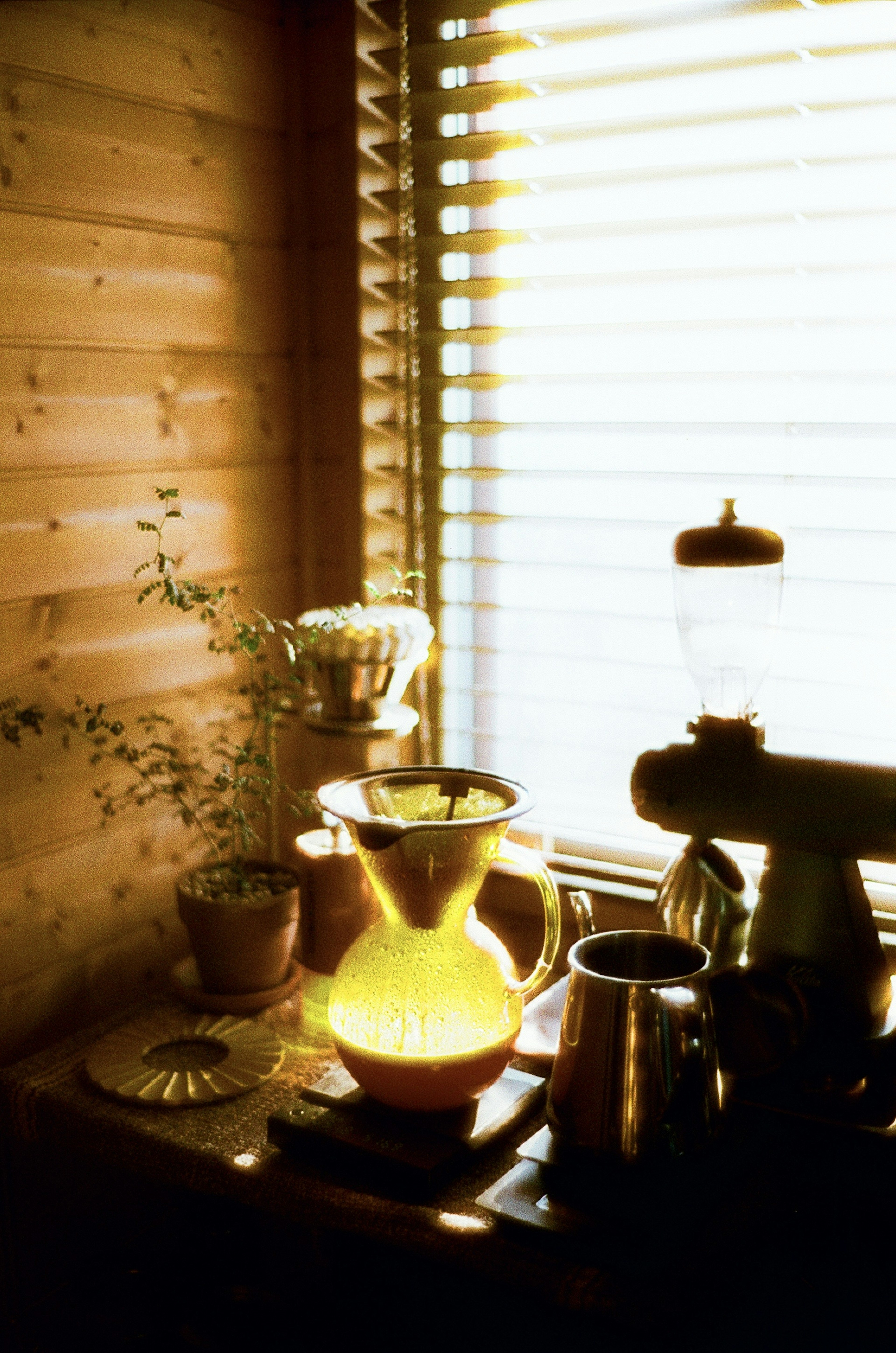 Warmes Interieur mit einer gelb-grünen Vase und einer Metallkanne am Fenster