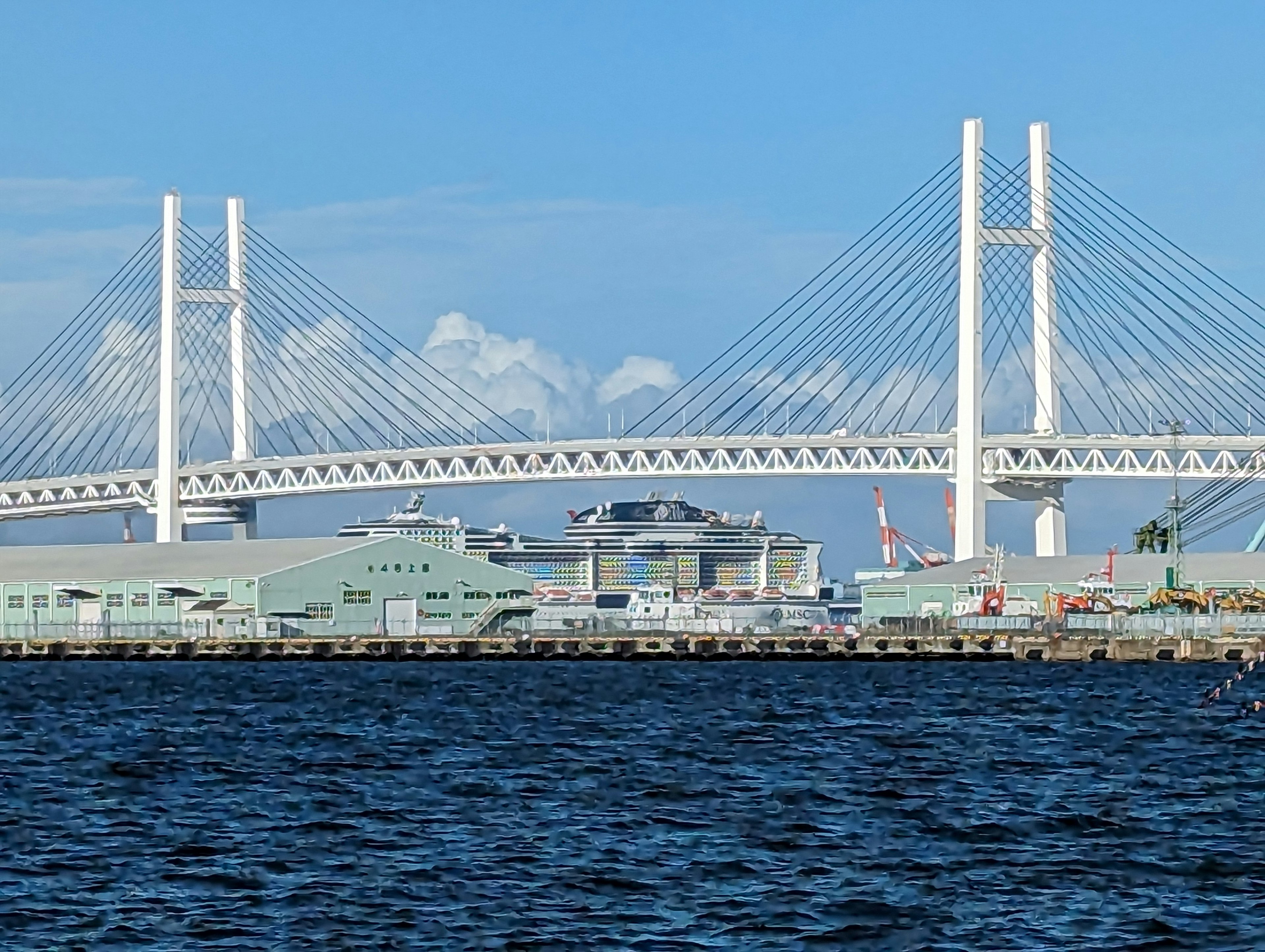 Yokohama Bay Bridge spanning over the blue waters with port buildings