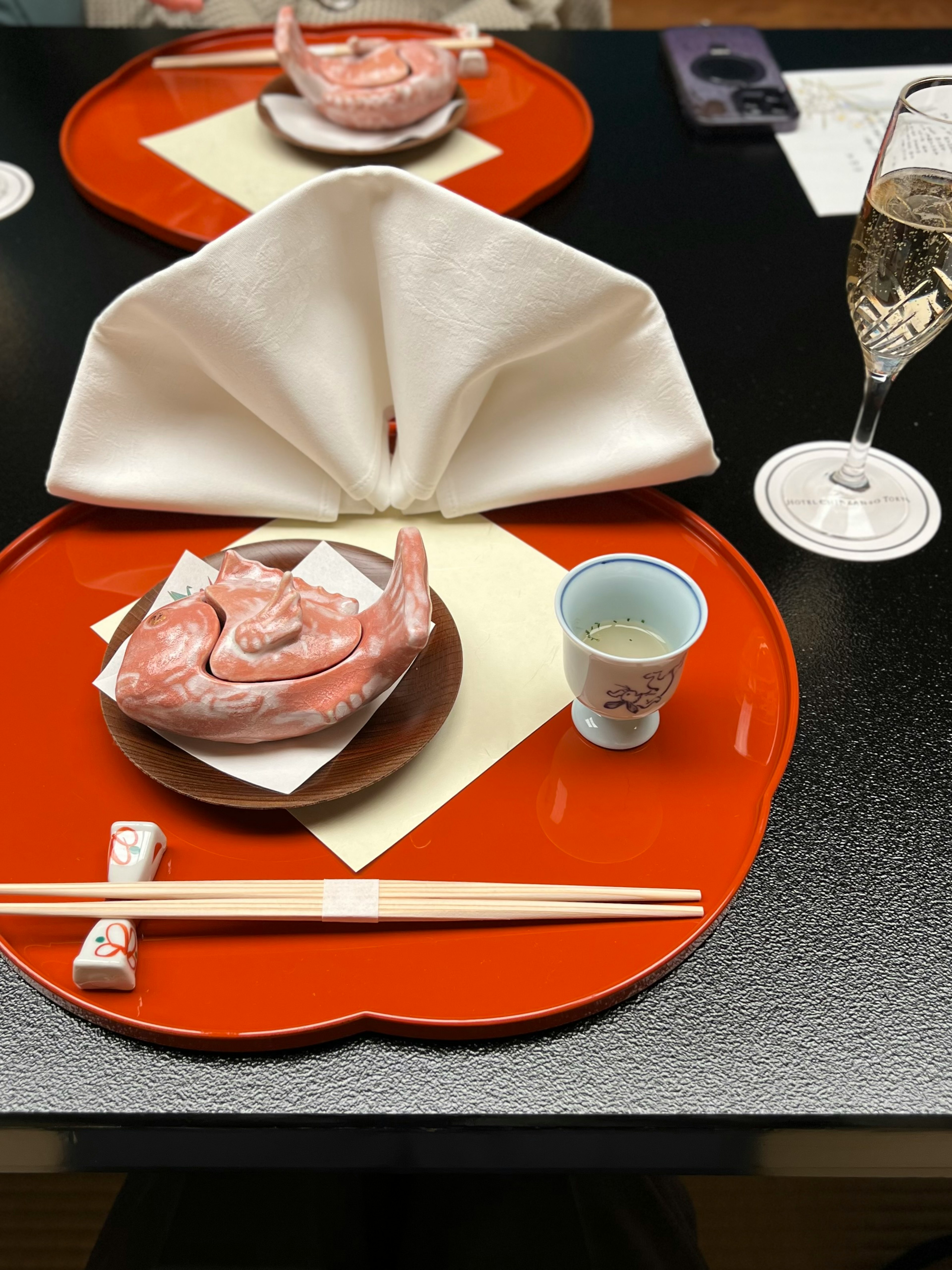 Japanese cuisine presentation on a red plate with a sake glass