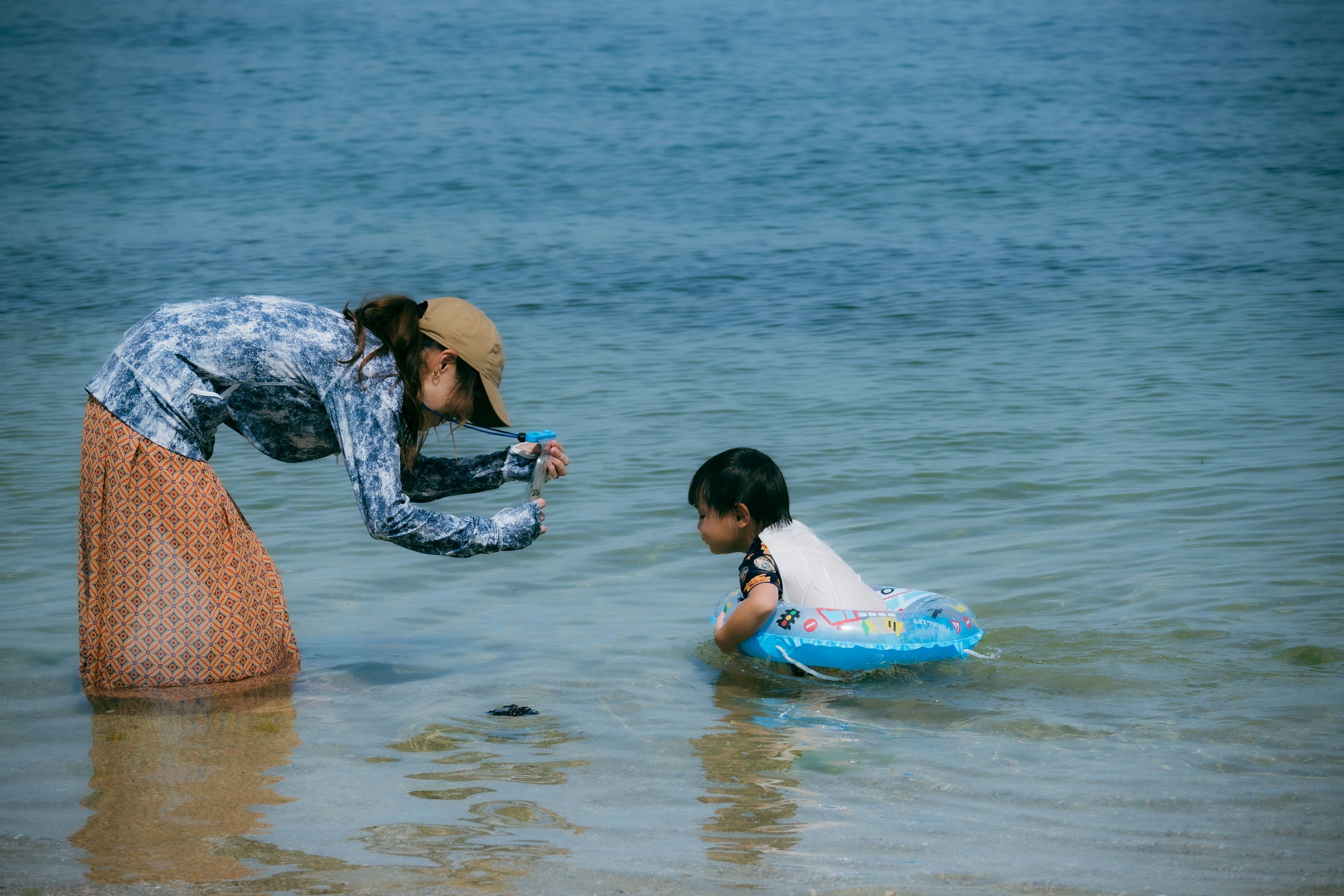 Mutter fotografiert ein Kind, das im flachen Wasser spielt