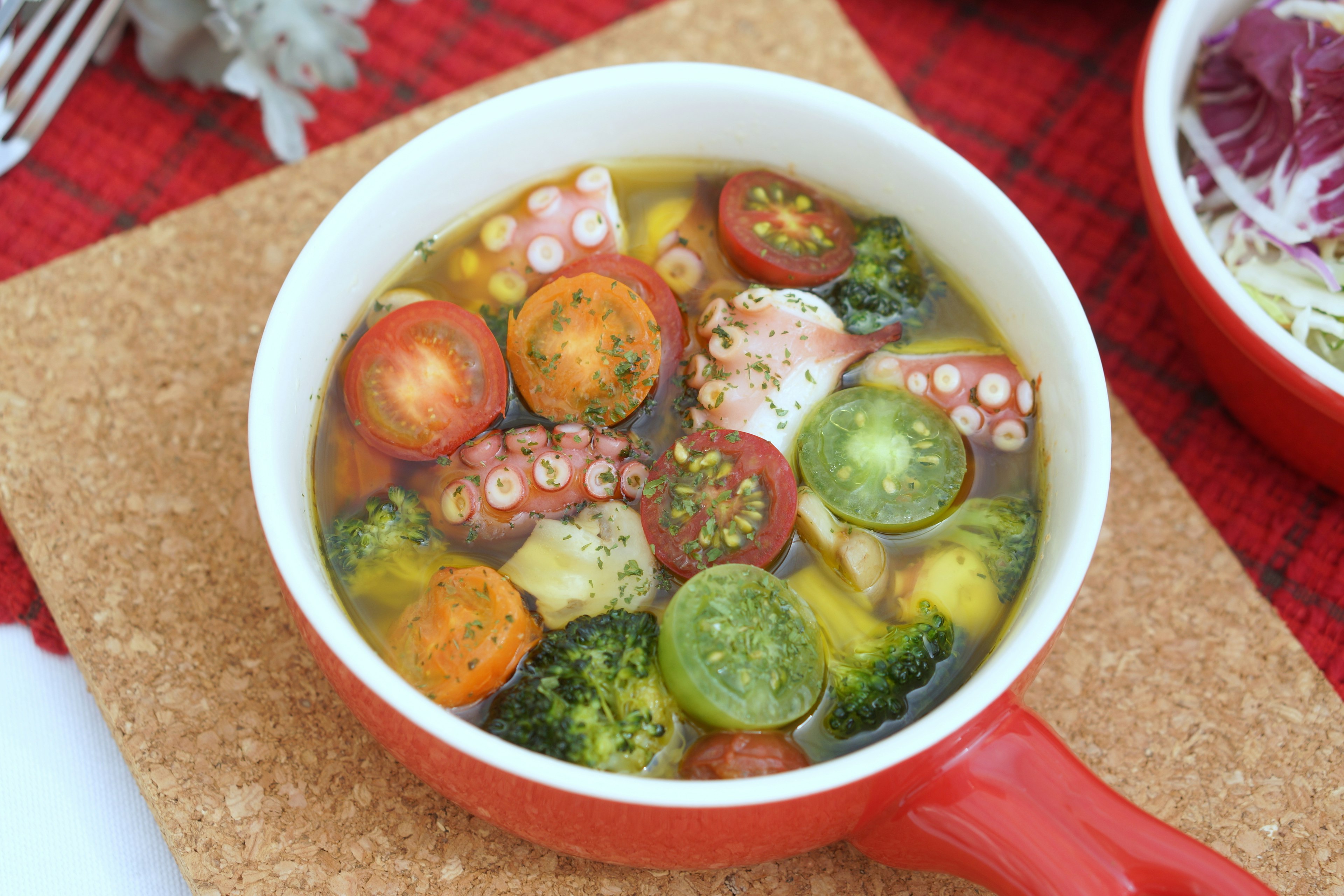 Sopa de verduras frescas y pulpo en una olla roja