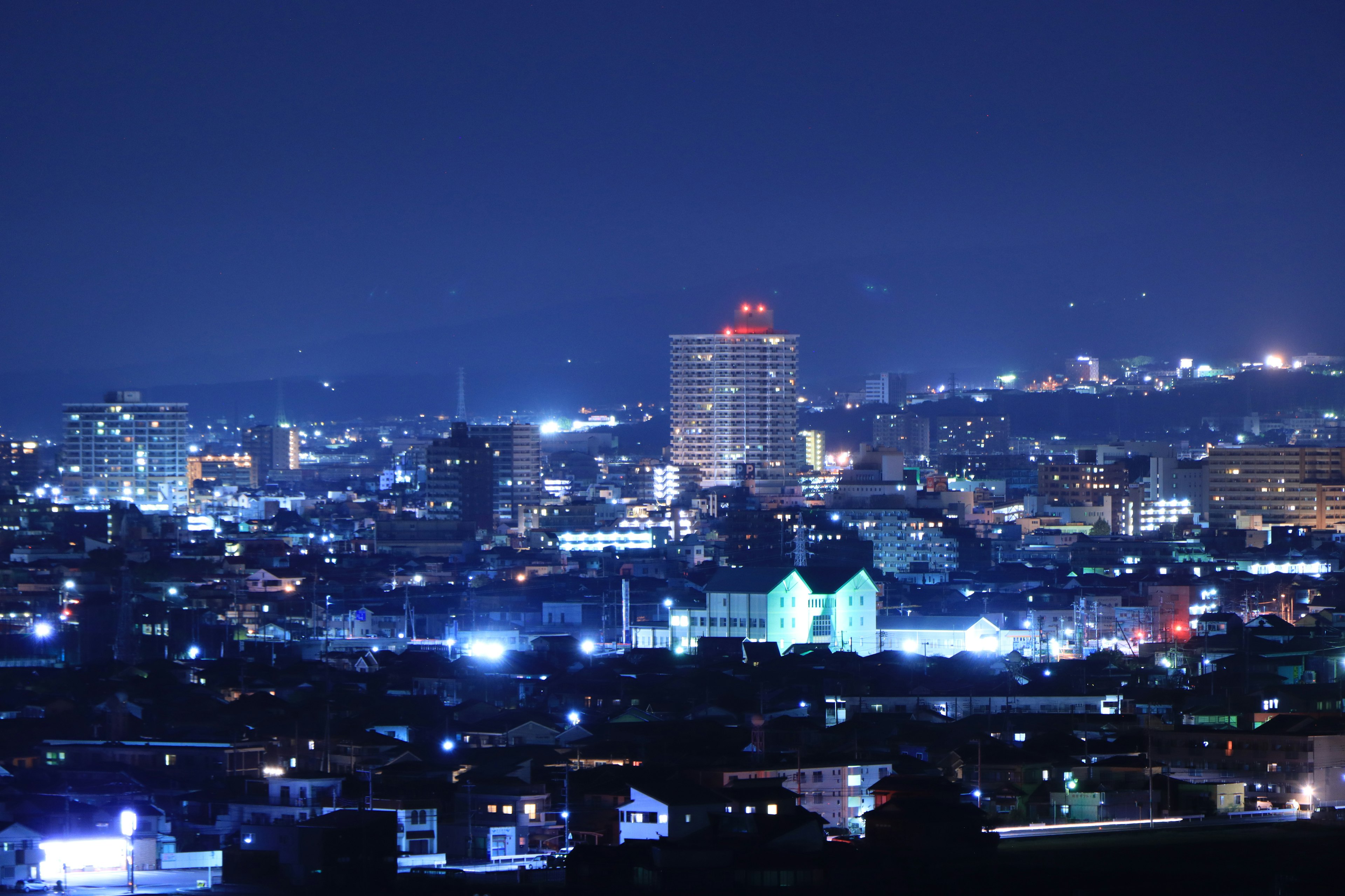 Night cityscape featuring skyscrapers and blue lights illuminated streets