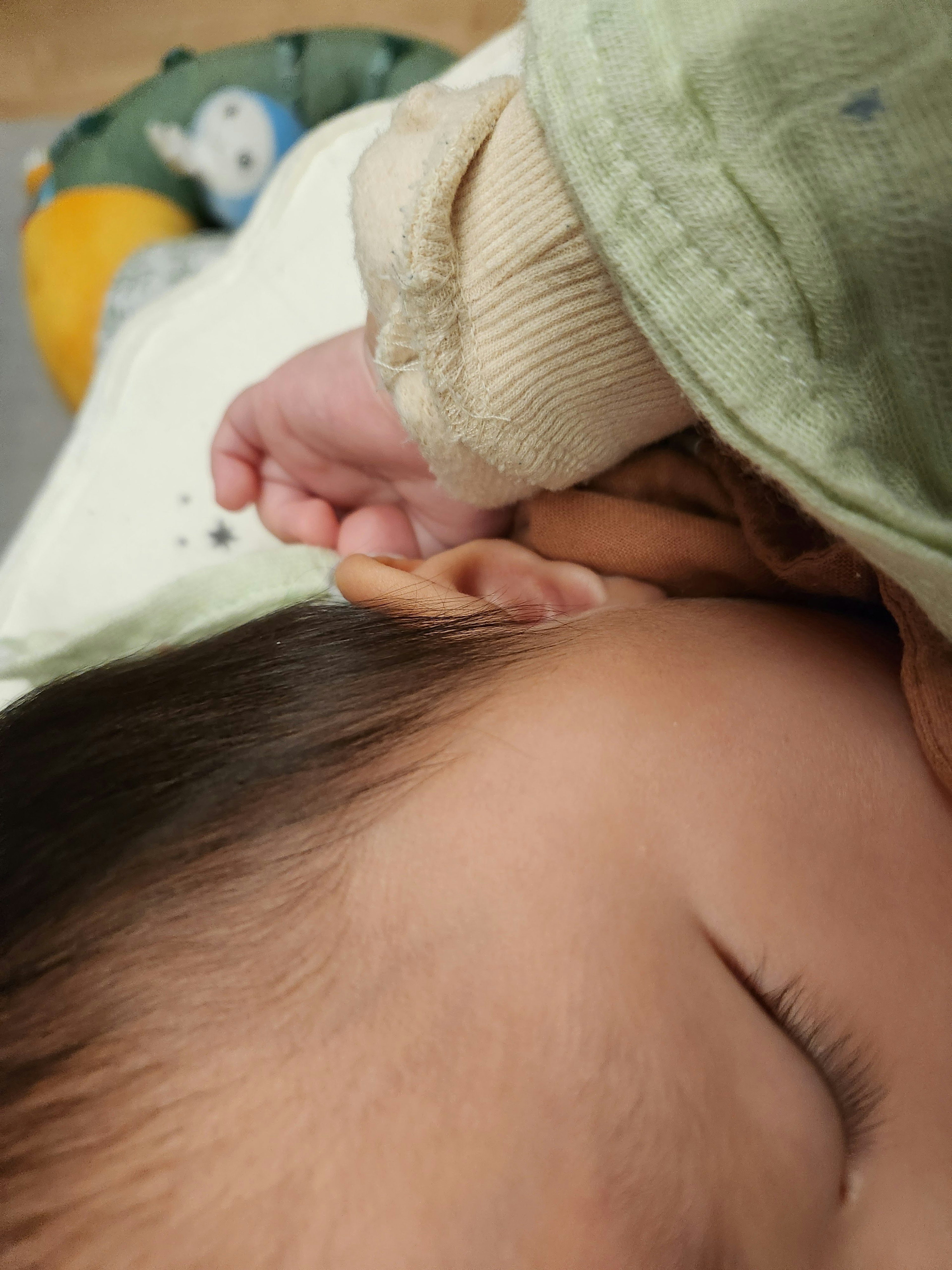 Un bambino che dorme con una mano che tocca l'orecchio