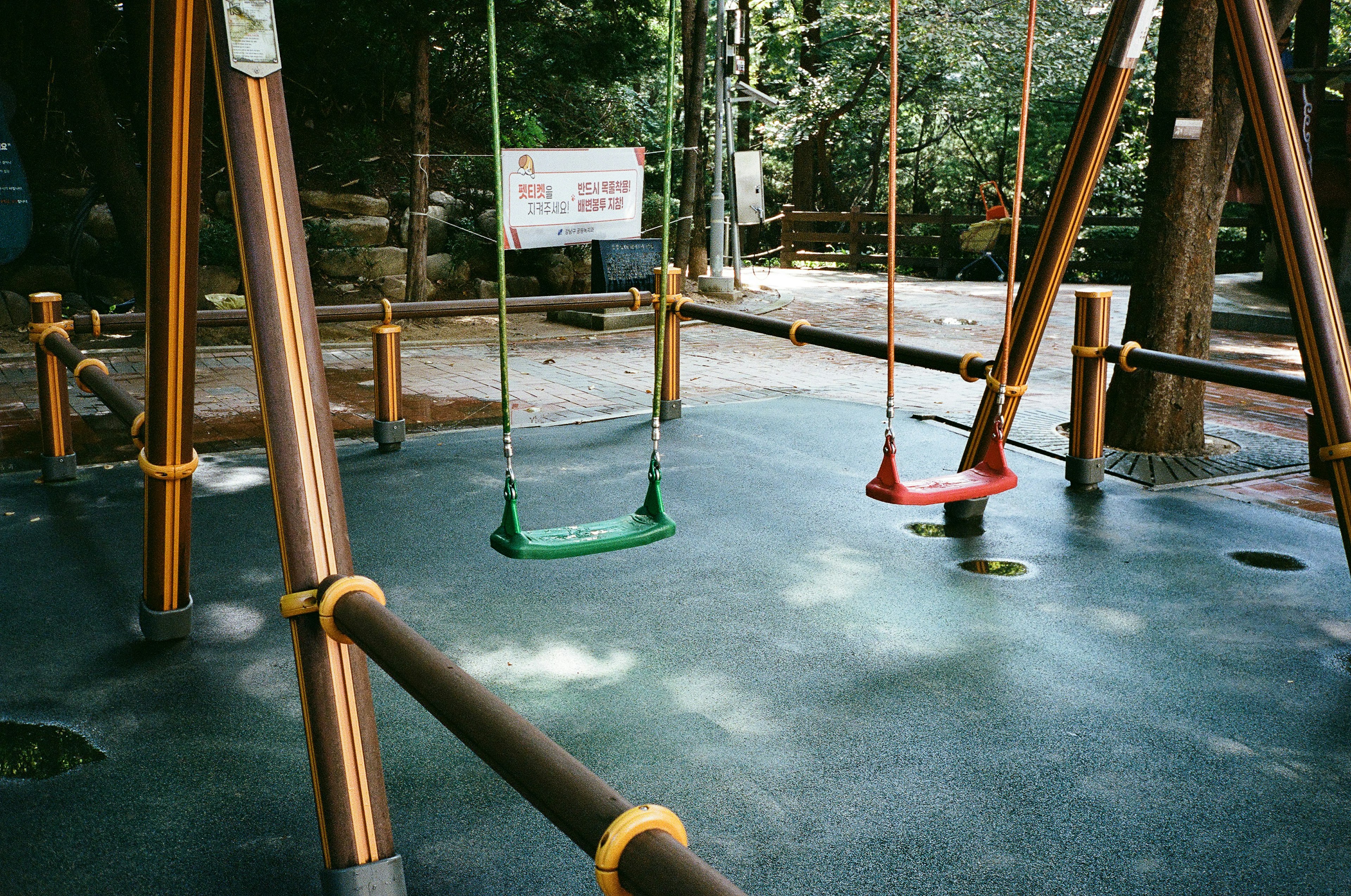 Playground scene featuring swings in green and red colors