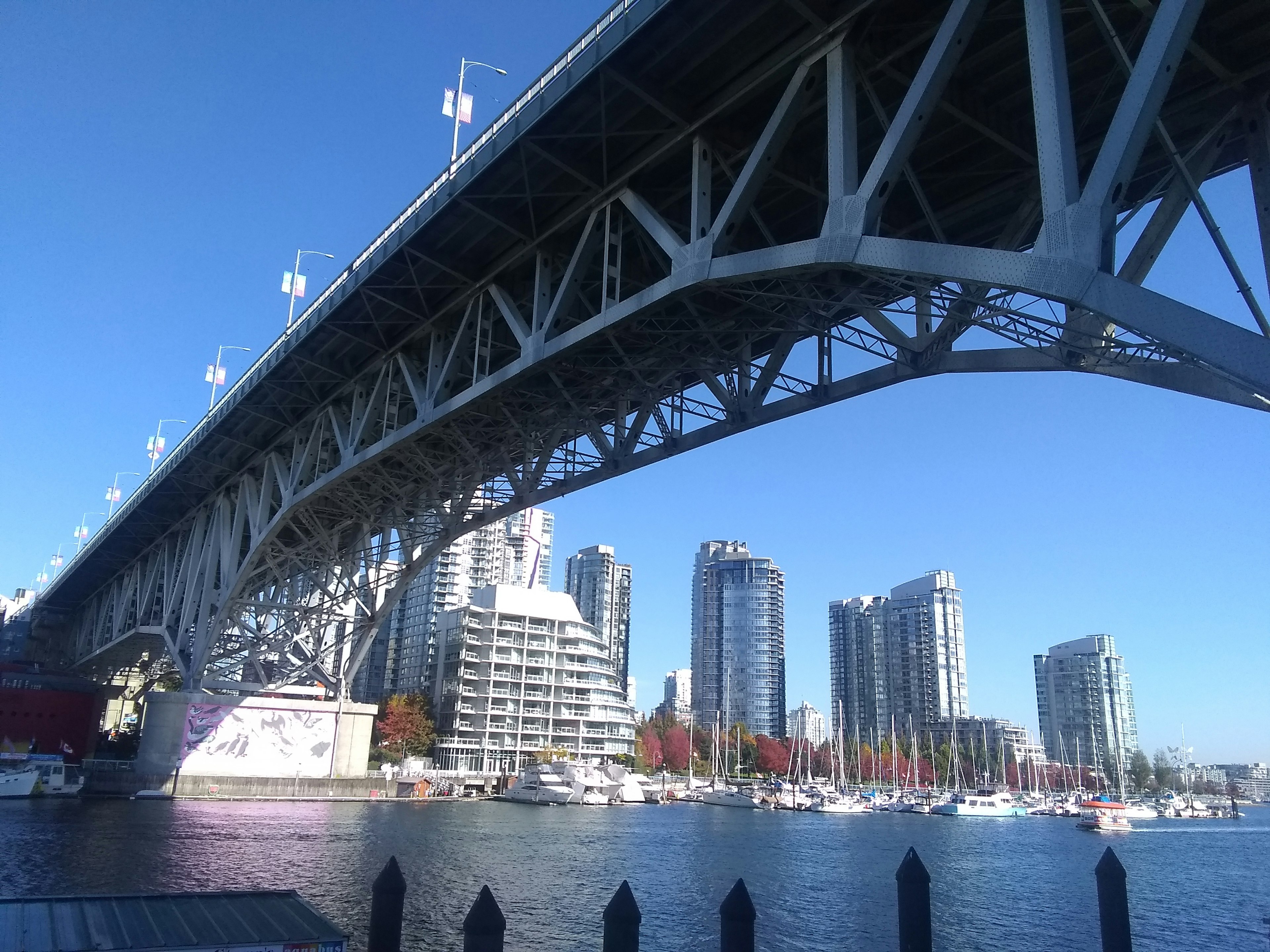 View of city skyscrapers and yachts from under a bridge