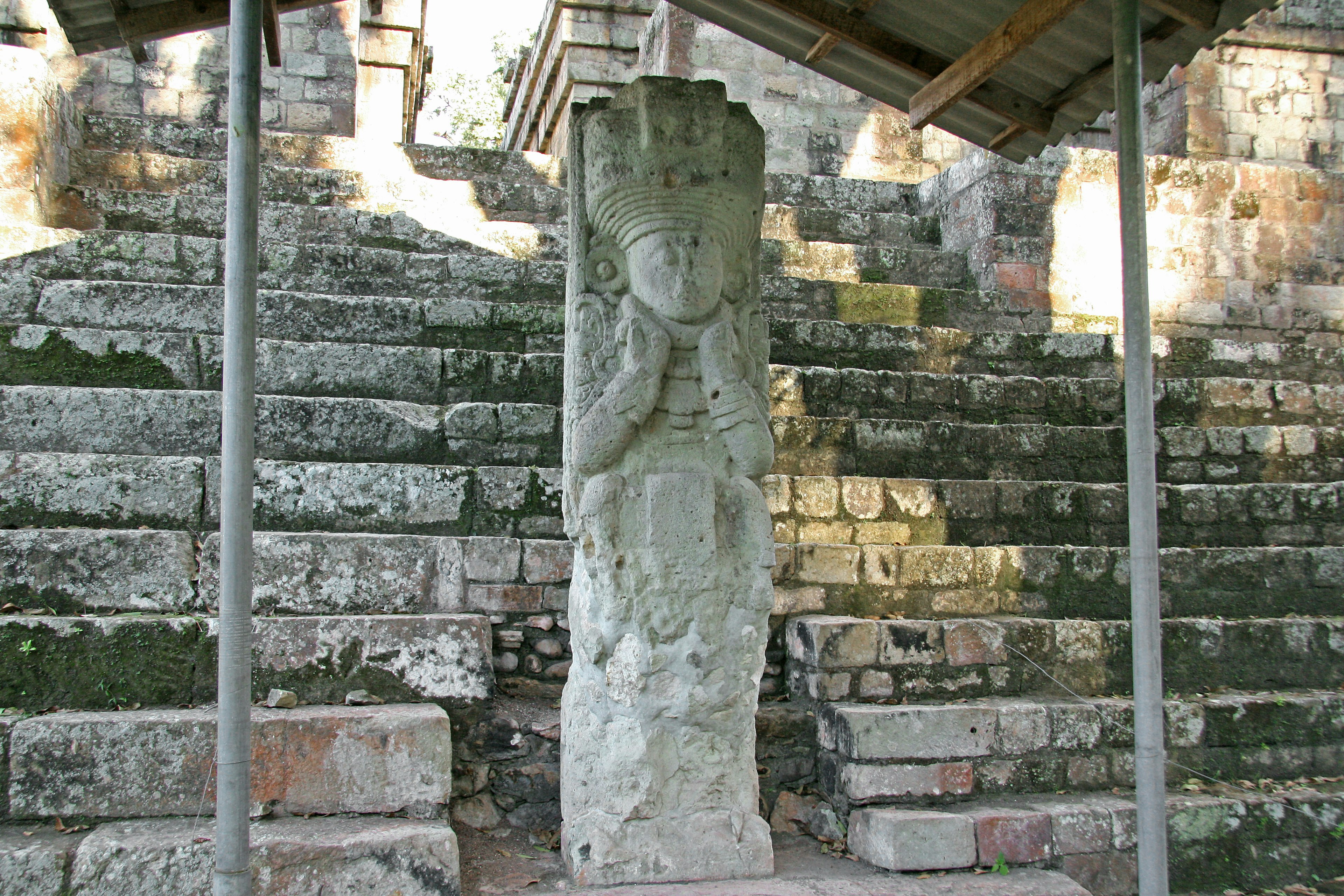 Antike Steinskulptur vor moosbedeckten Stufen Die Skulptur ist zentral platziert und wirkt abgenutzt