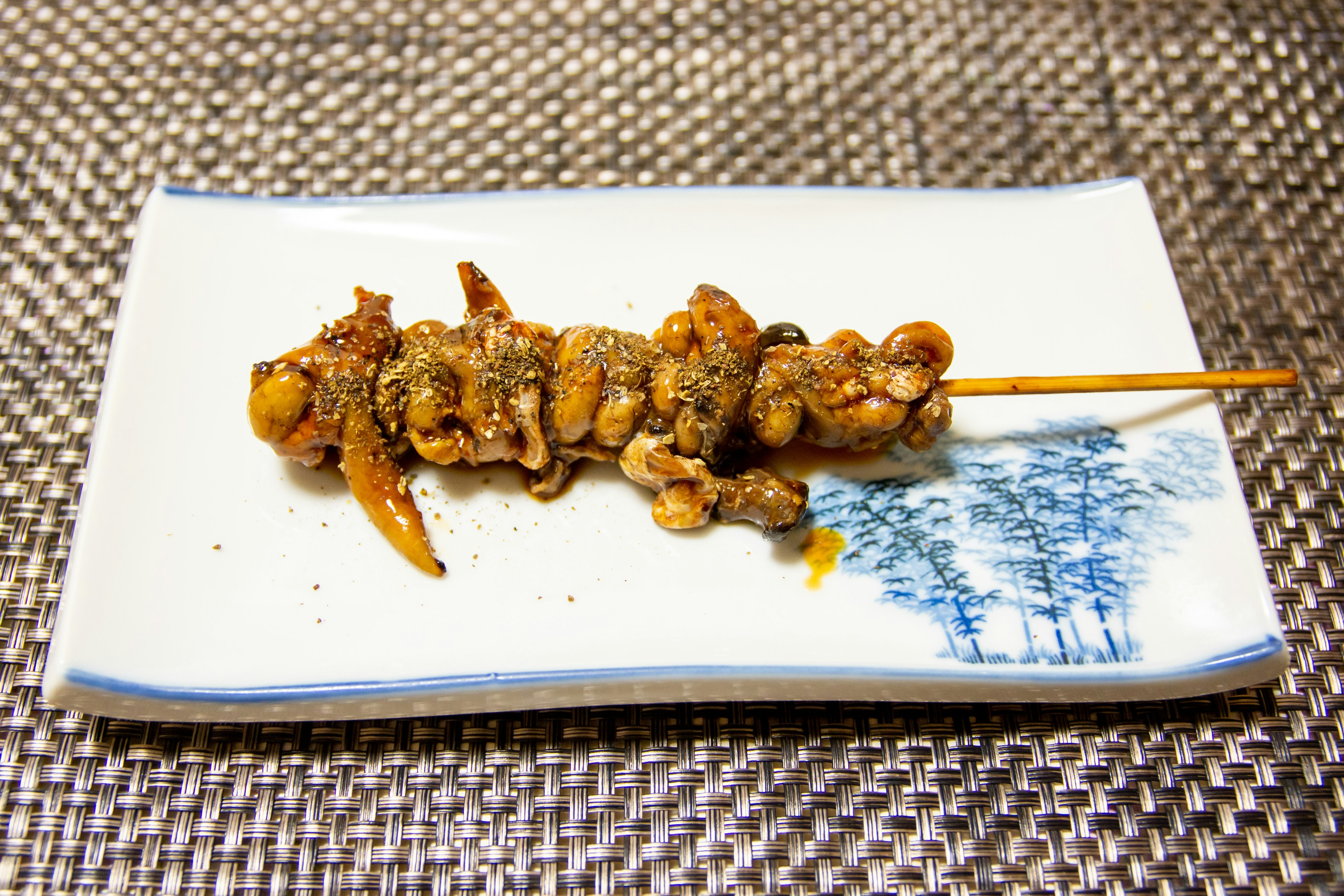 Comida a la parrilla en brocheta sobre un plato blanco con diseño azul