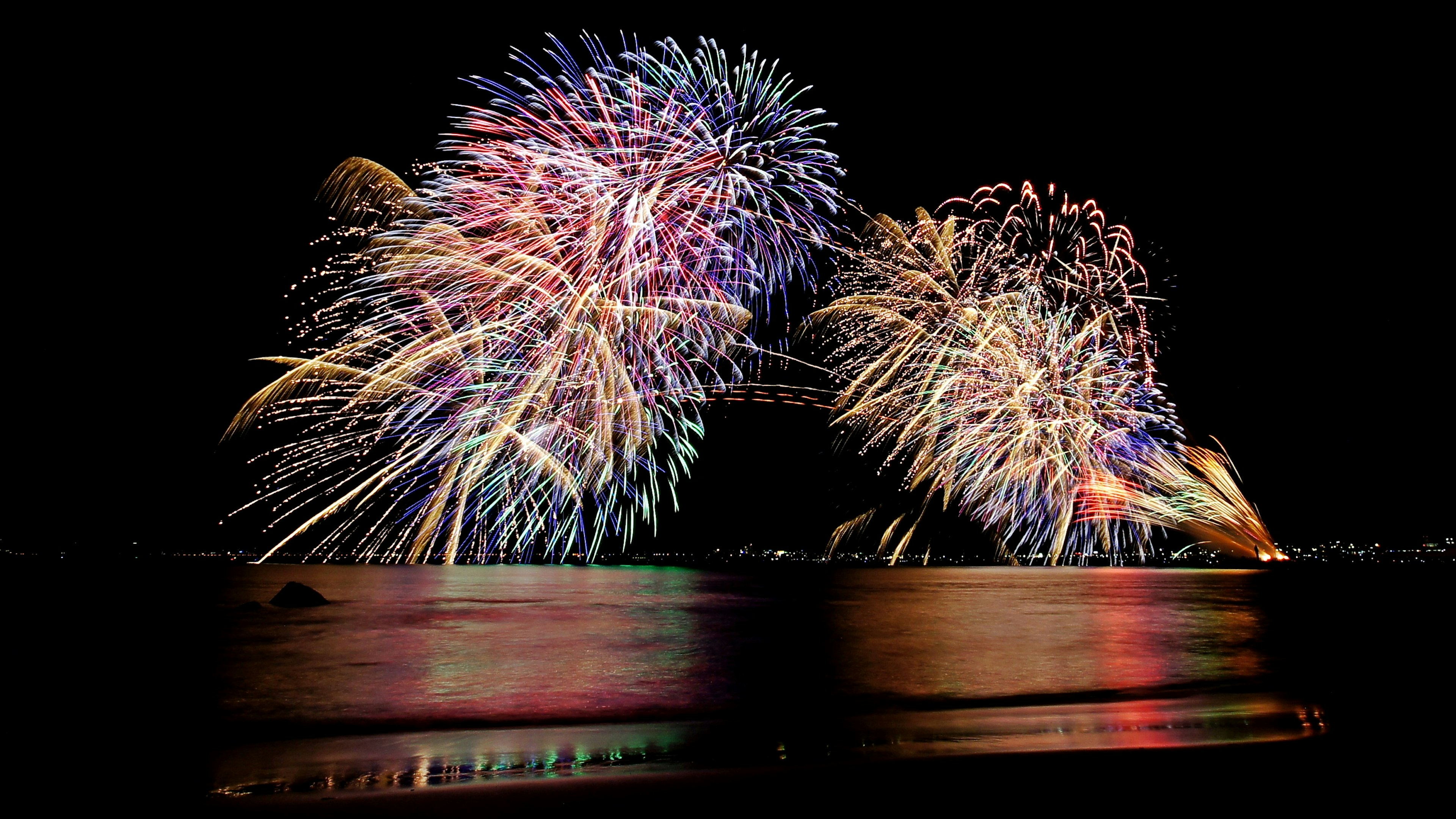 Fuochi d'artificio colorati che illuminano il cielo notturno sopra l'acqua