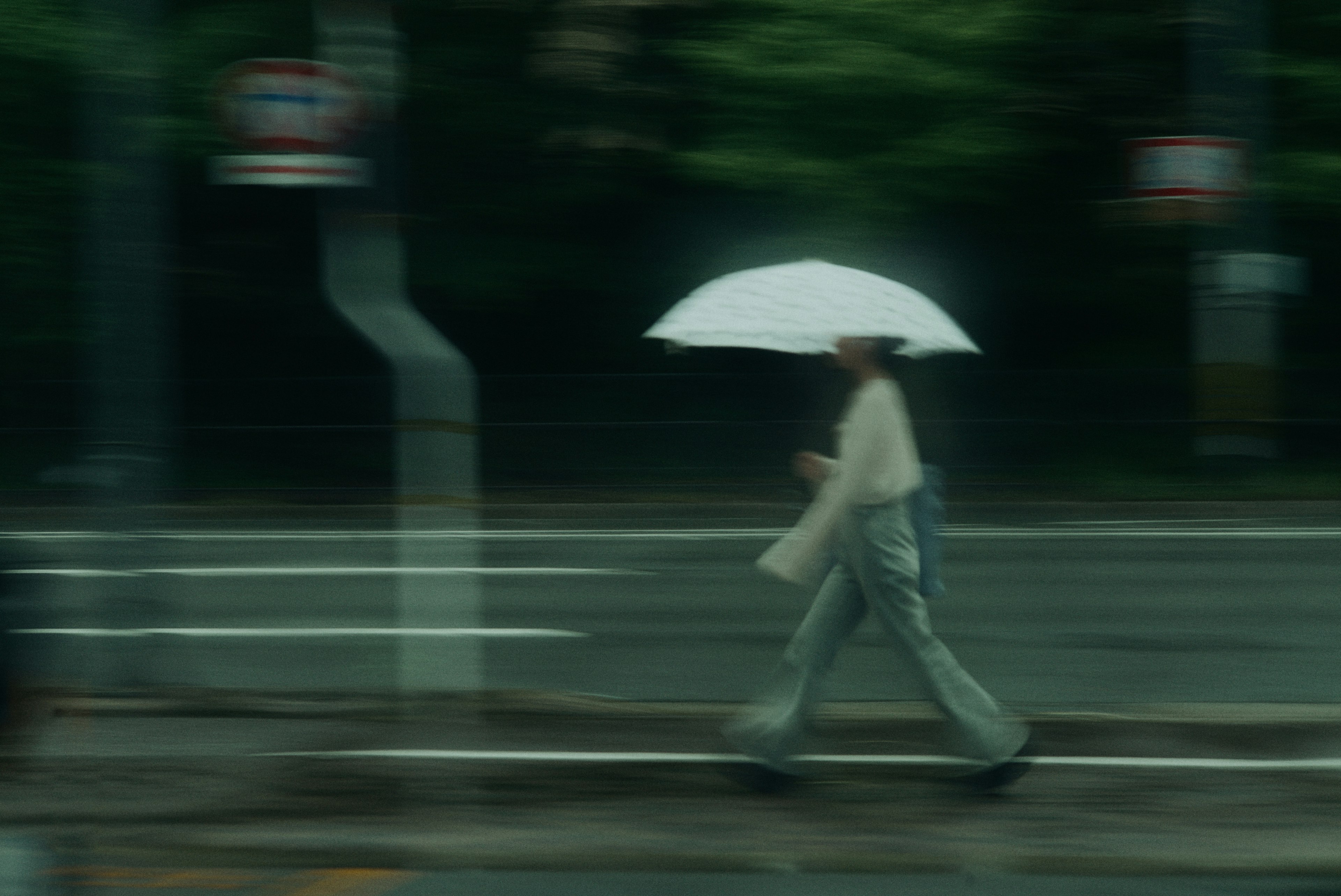 Eine Person, die mit einem Regenschirm in einem verschwommenen Hintergrund geht