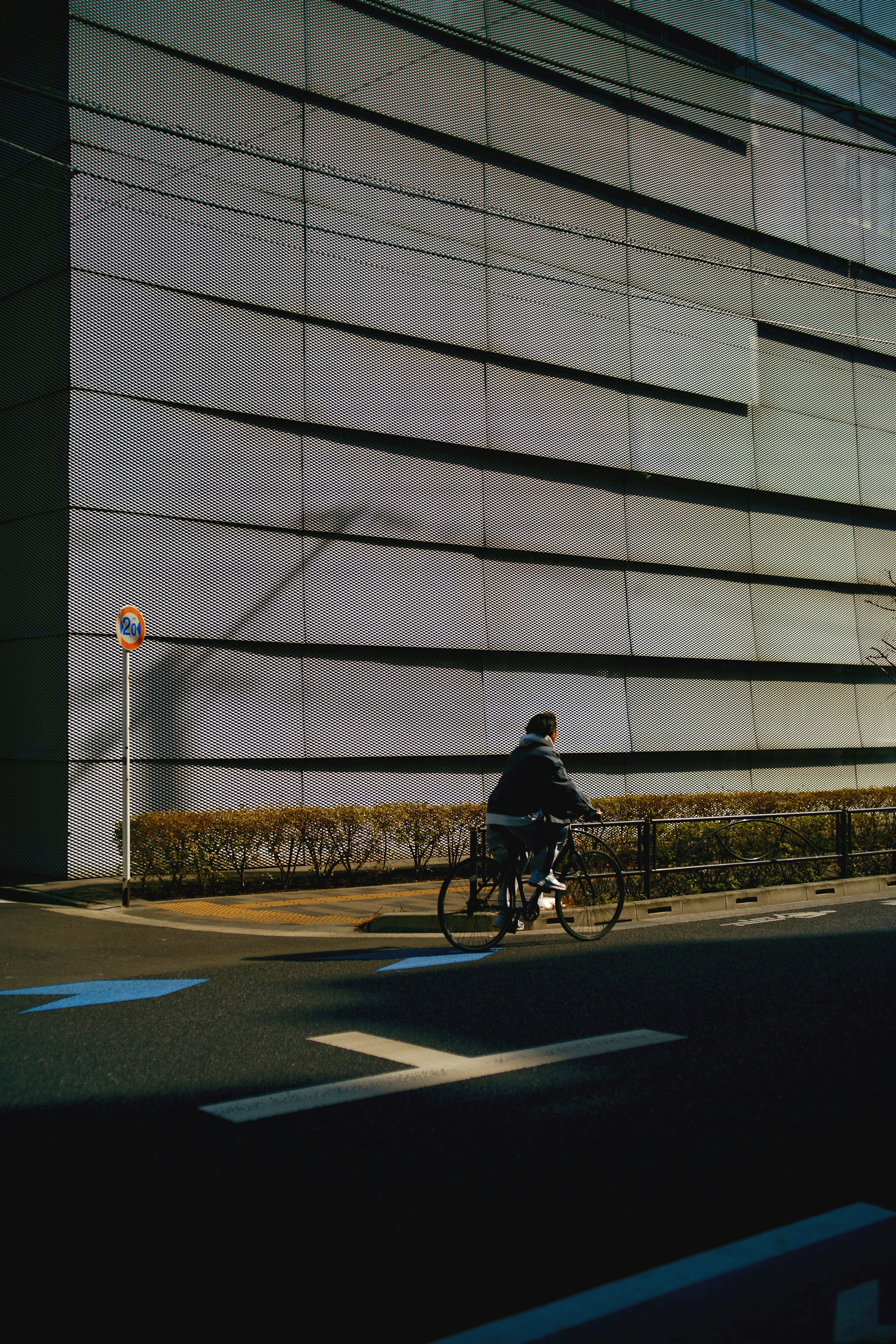 自転車に乗る人が現代的な建物の壁の前を通り過ぎるシーン