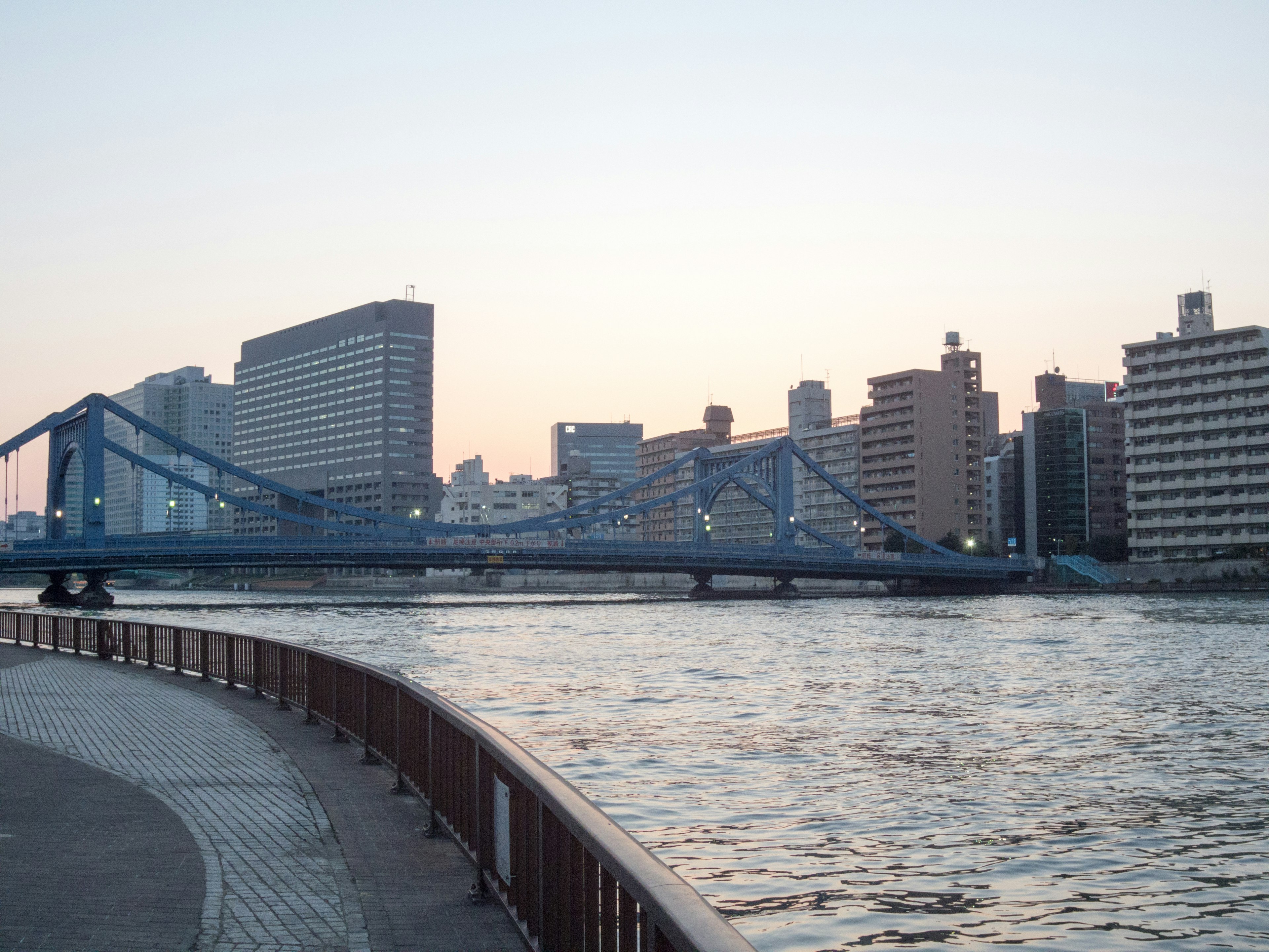 Vista escénica de un puente azul y rascacielos al atardecer