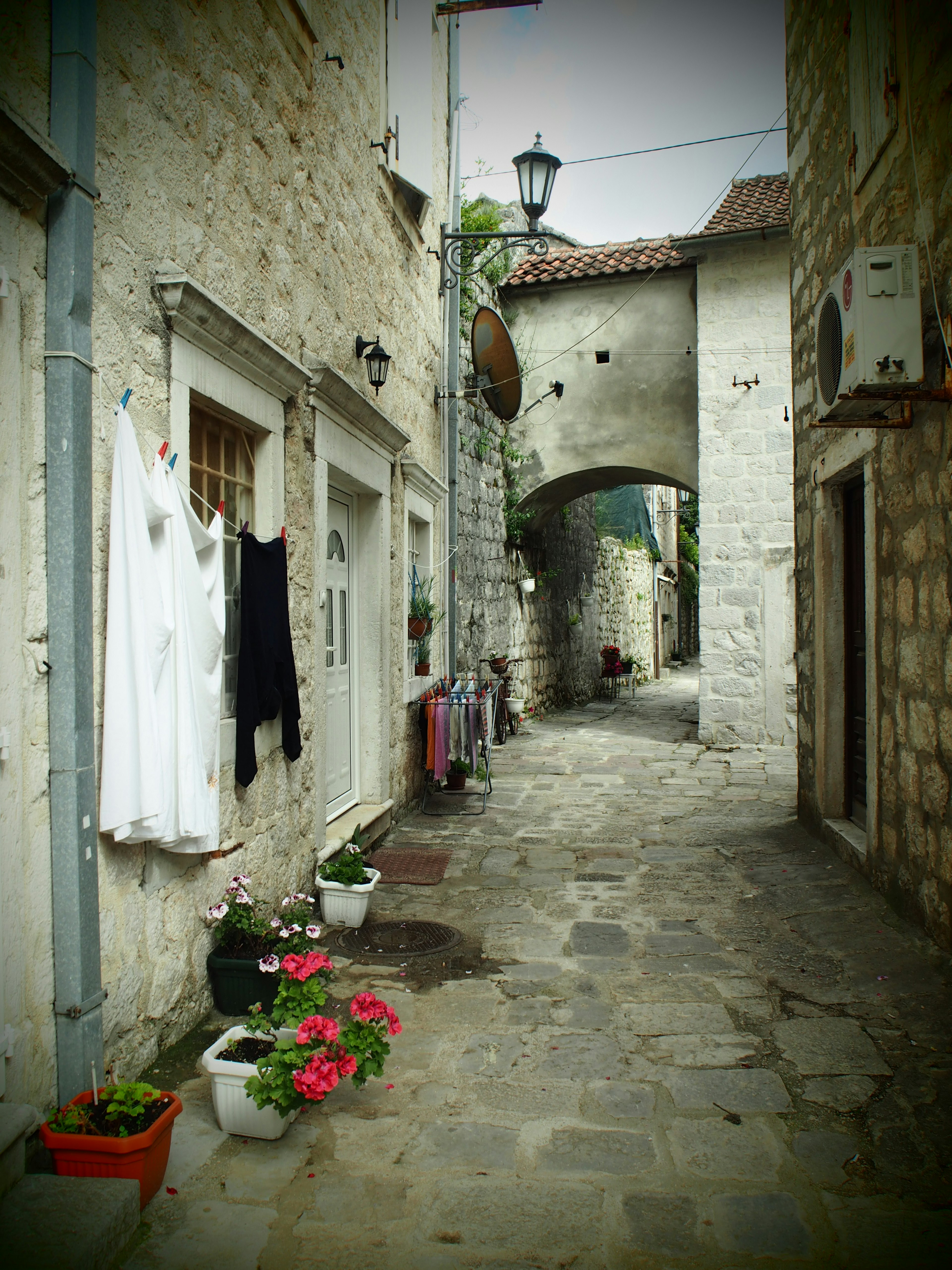 Narrow alley en pierre avec des vêtements blancs suspendus et des pots de fleurs