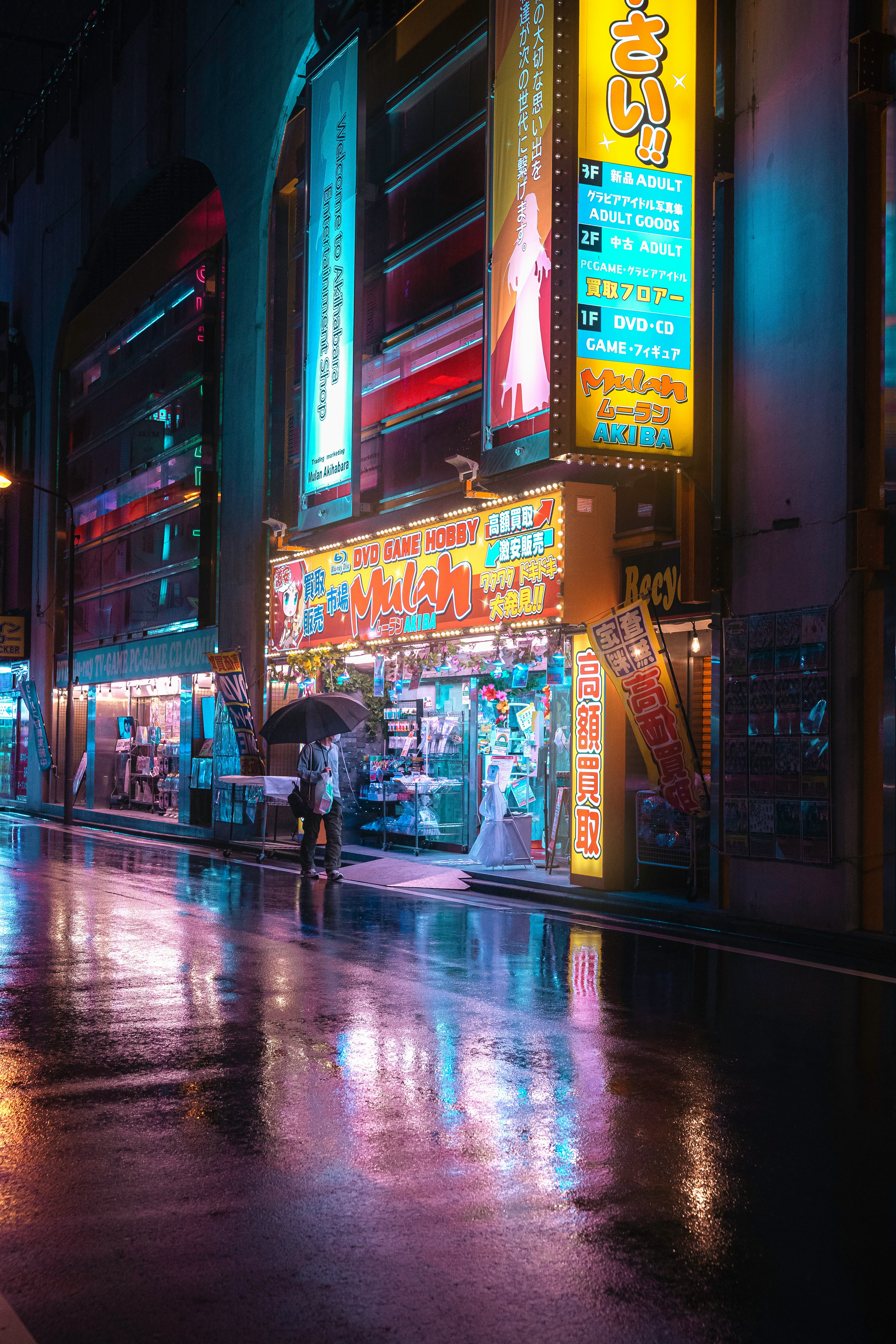 雨に濡れた街の夜景 brightly lit neon signs reflect on wet pavement