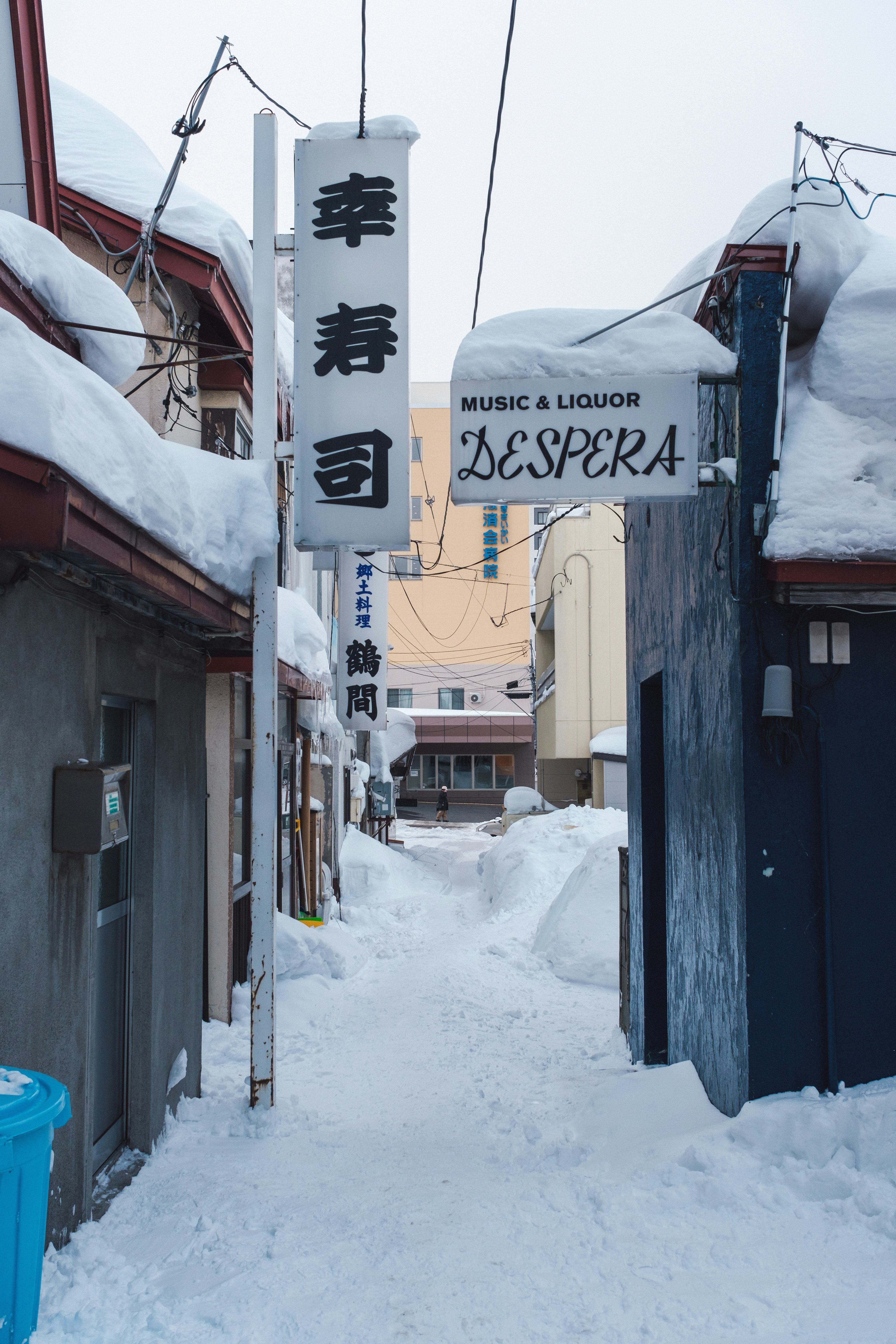 Calle estrecha cubierta de nieve con letreros de restaurantes