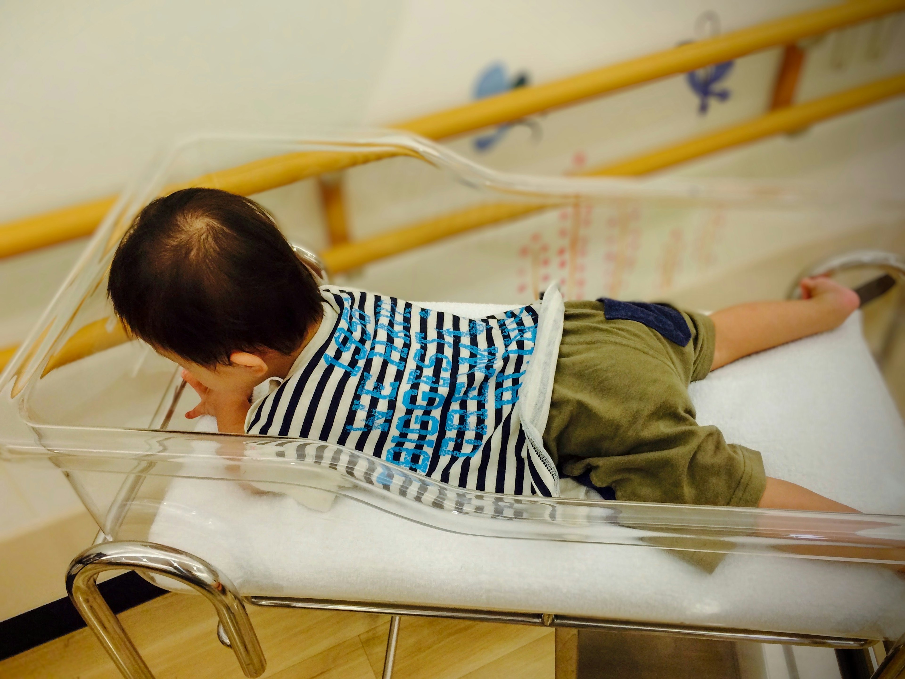 A baby lying on a transparent bassinet