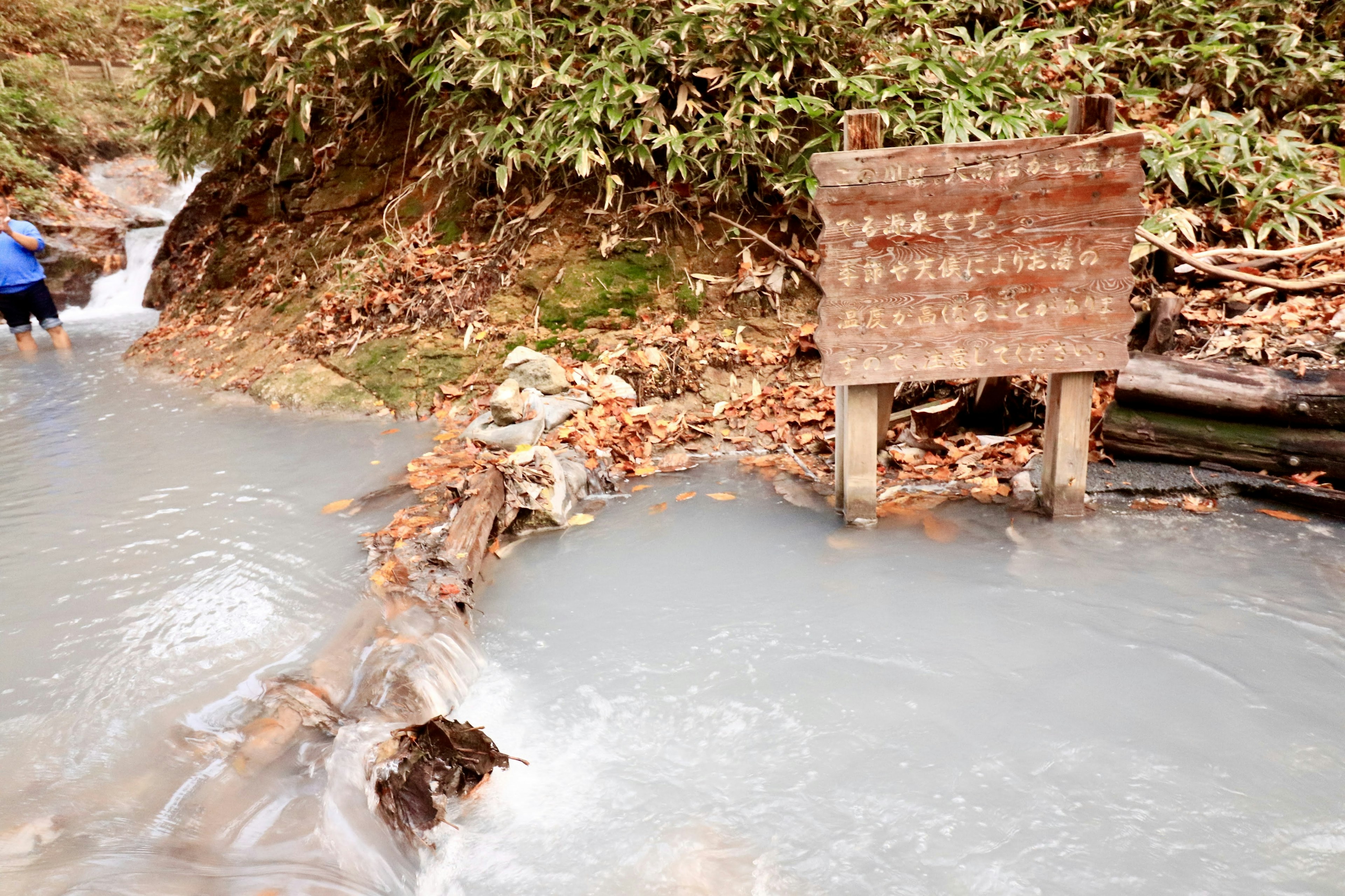 小川の近くにある木製の標識と水の流れ