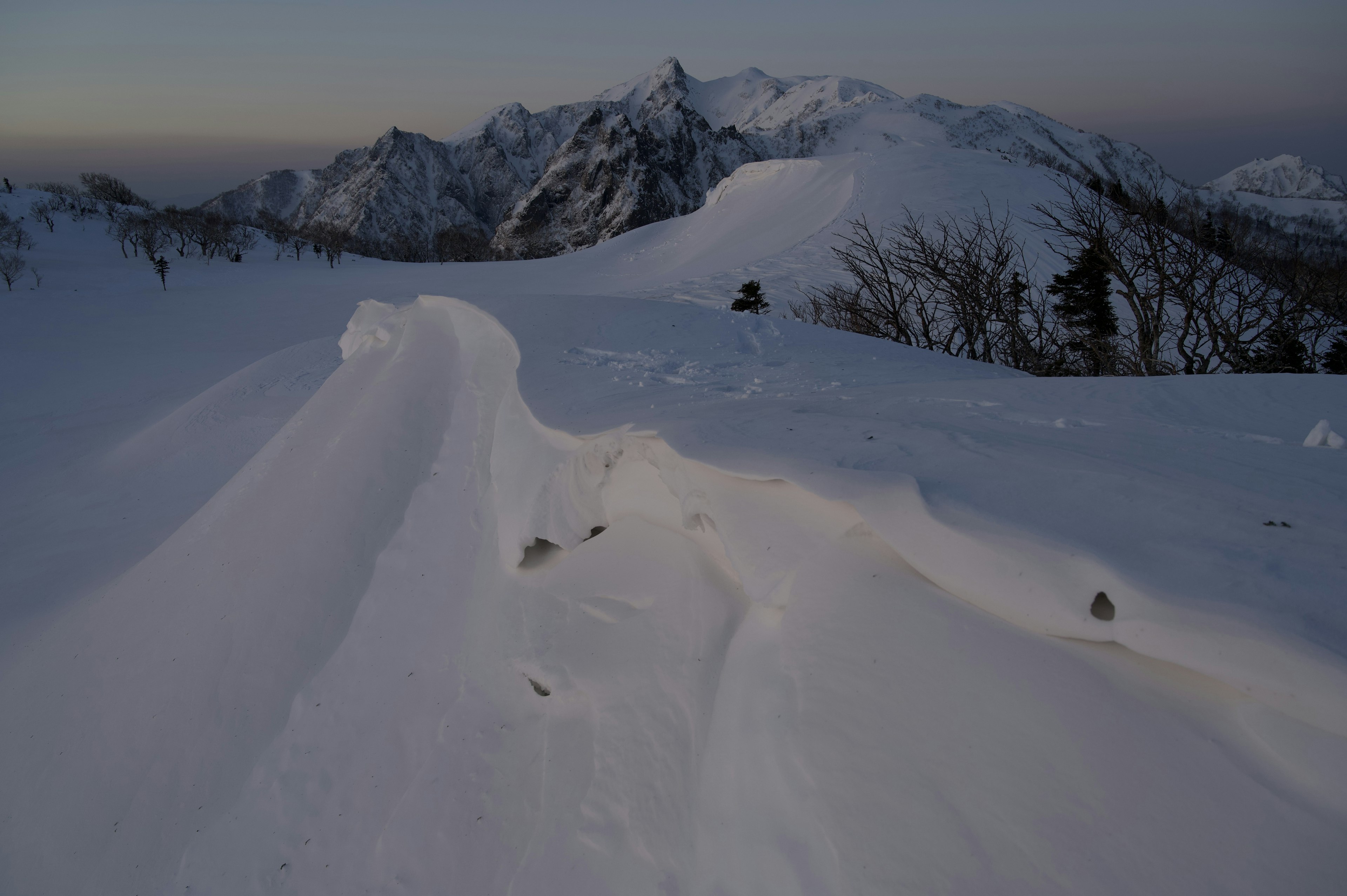 Paesaggio montano coperto di neve con formazioni di neve ondulate