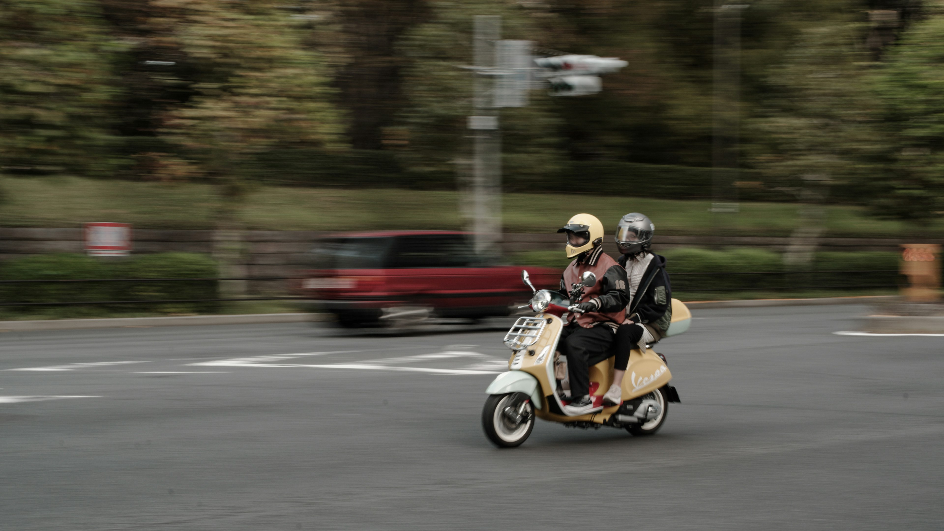 Zwei Fahrer auf einem Roller, die durch die Straße fahren