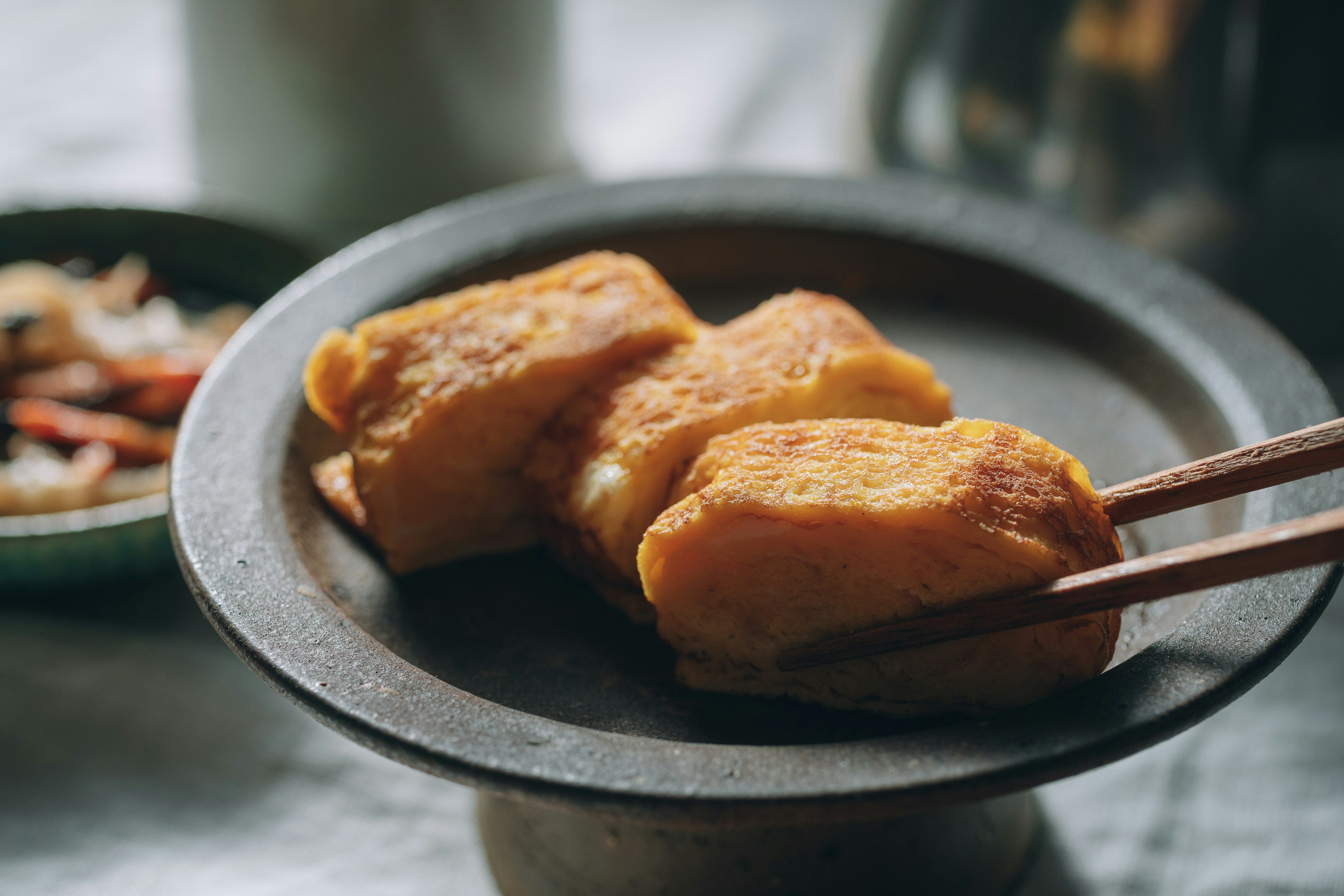 Tahu goreng disajikan di piring dengan sumpit