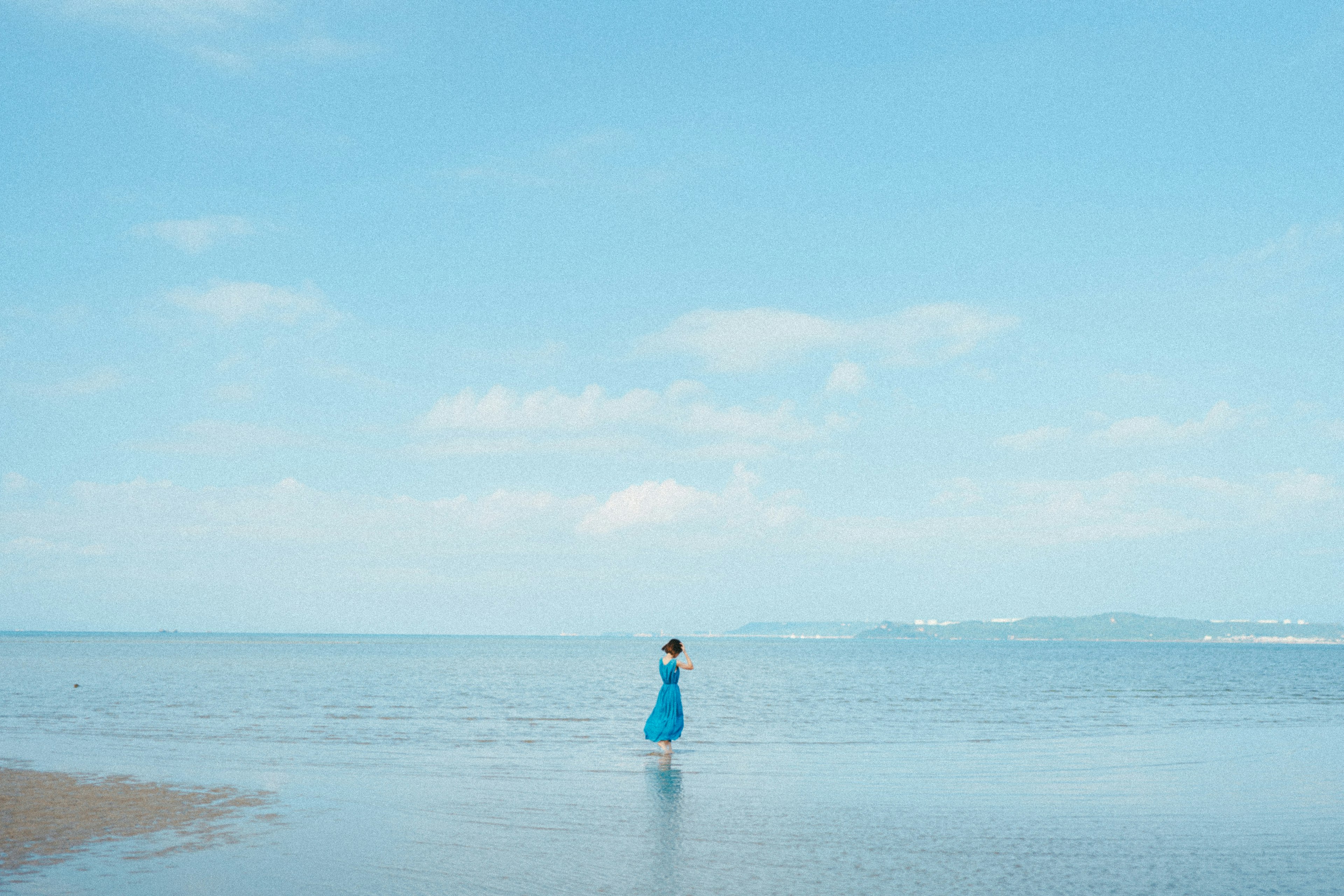 穿著藍色連衣裙的女人站在海中